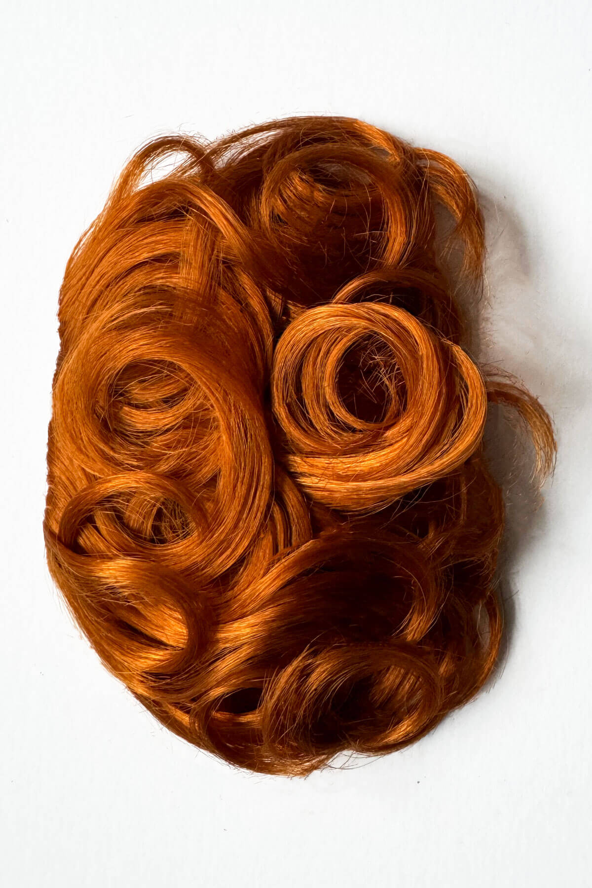 Reddish-brown hairpiece on a white background. Curly 1940s style clip-in fringe hairpiece/clip-in bangs: Bunny ginger
