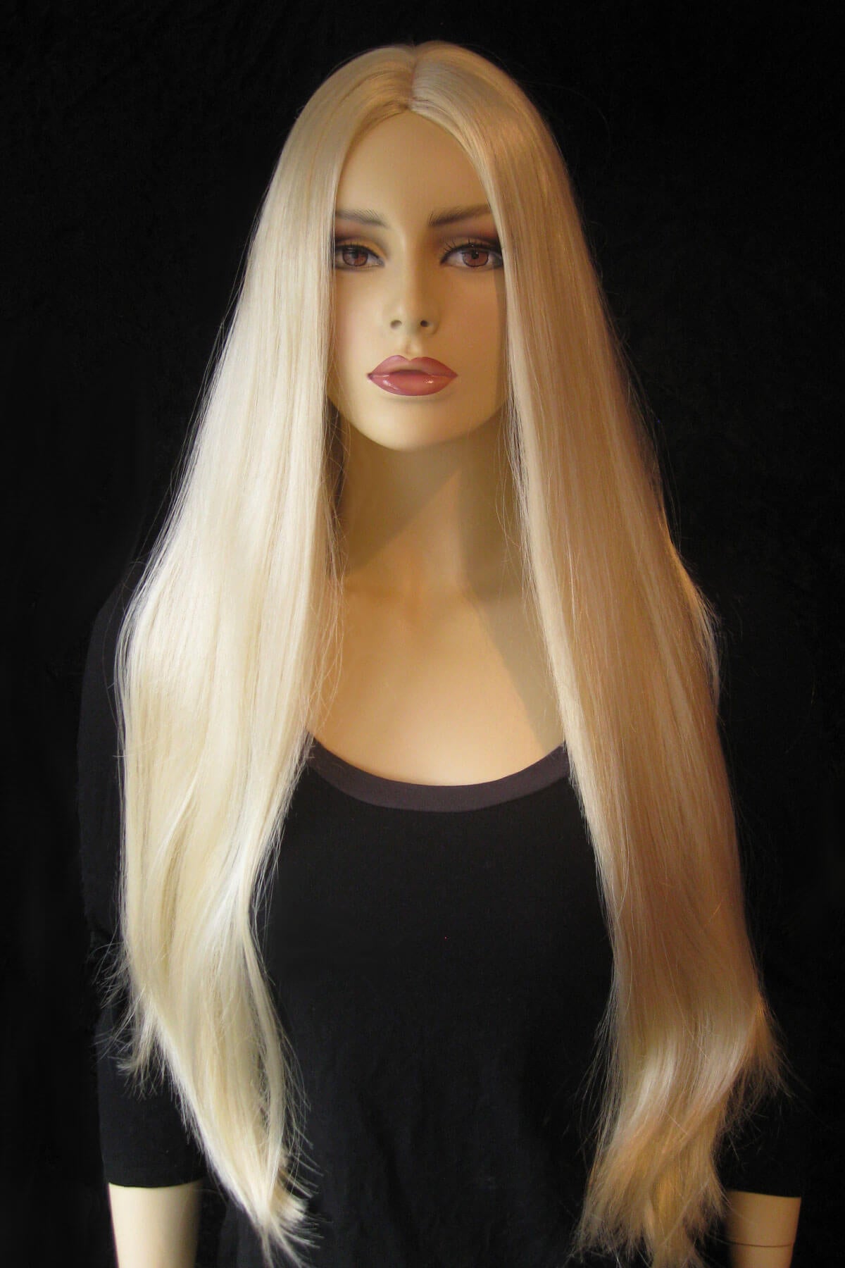 Mannequin head with long blonde wig on a black background. Long straight blonde wig with no fringe: Juste