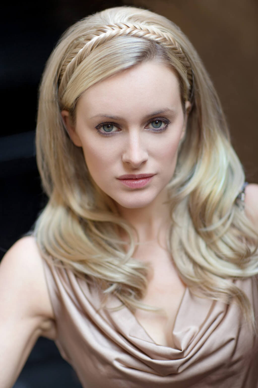 A close-up portrait of a blonde woman wearing a metallic champagne-brown draped top and a matching braided headband. Fishtail plait hairband (braid) blonde 24H613