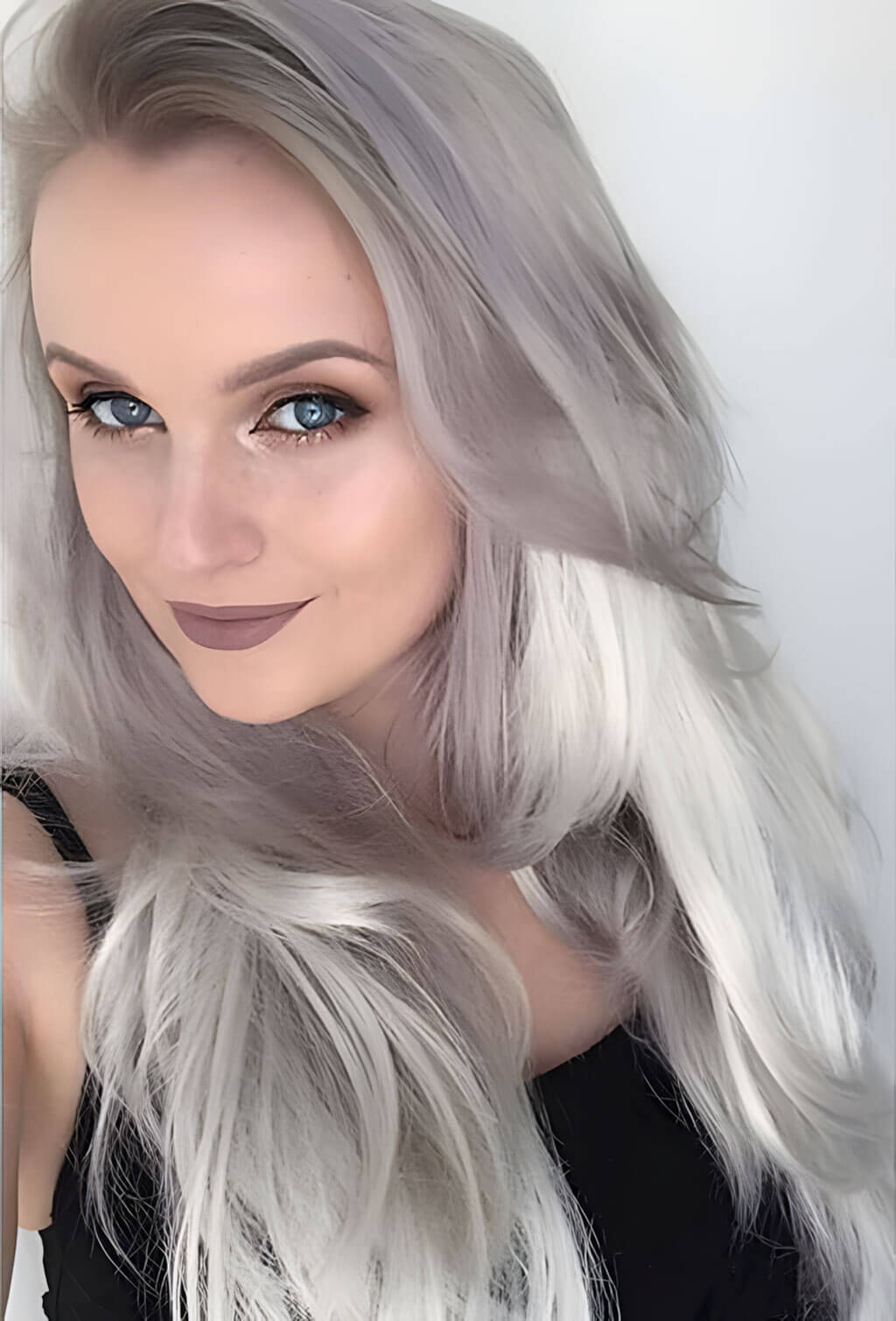 Woman with long, wavy, silver hair against a white background. Silver half wig hairpiece (3/4 wig), loose curls: Tahlia