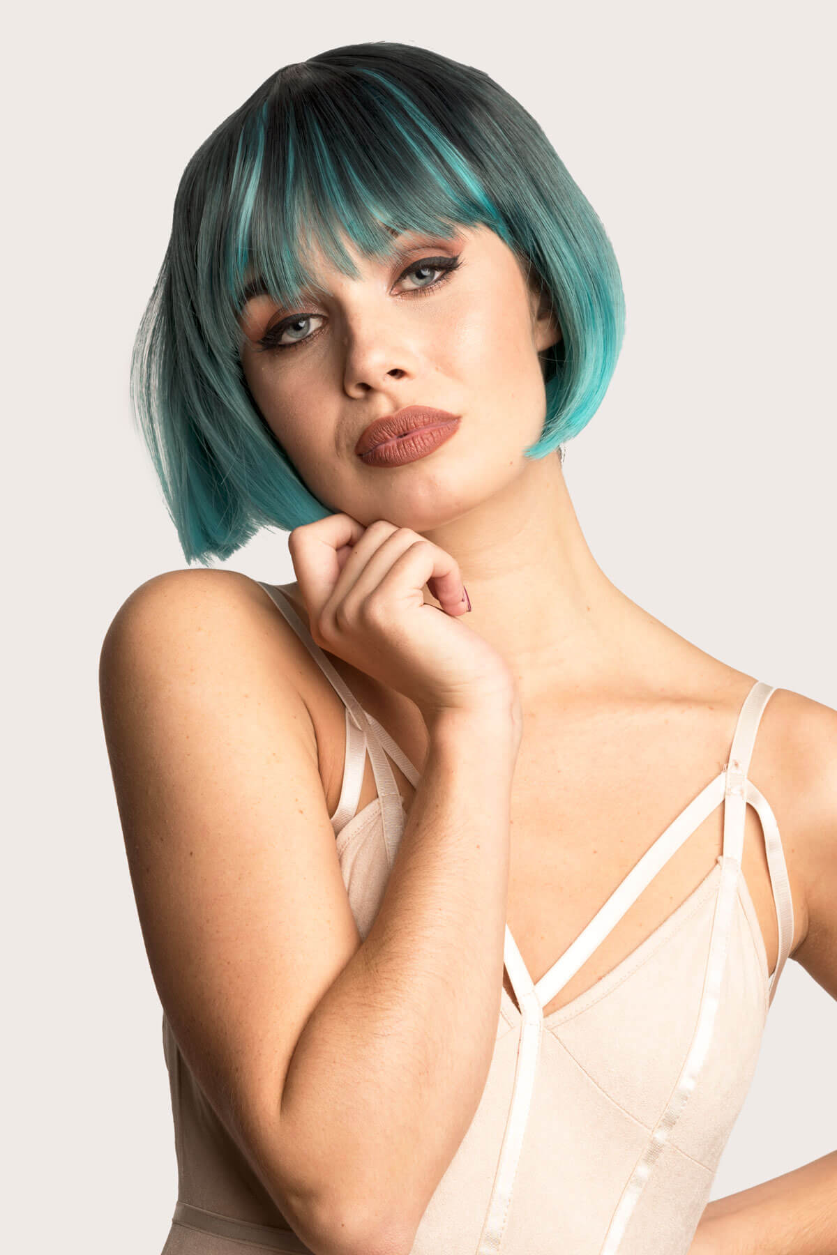 Woman with teal hair posing against a white background. Bob wig, black ombre blending to turquoise blue: Amara