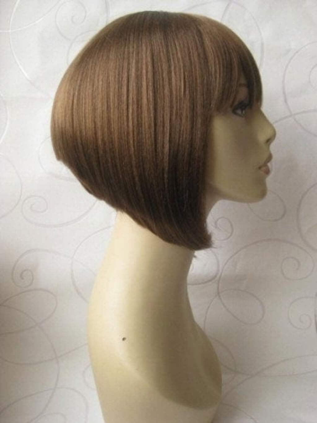 A straight, shoulder-length brown wig with side-swept bangs displayed on a beige mannequin head against a light patterned backdrop. Brown inverted bob wig, inverted/A-Line style: Colette light brown 12