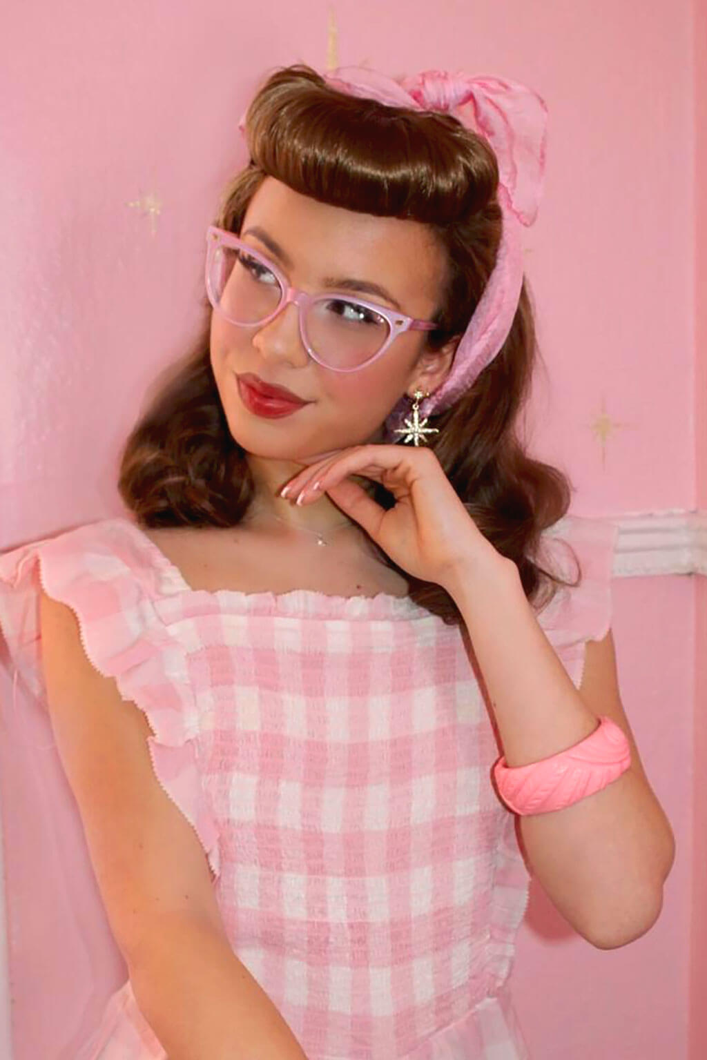 Woman in a pink checkered dress with glasses and a headband against a pink background. Bumper bangs pack - vintage 40s 50s fringe roll: Lena brown 12