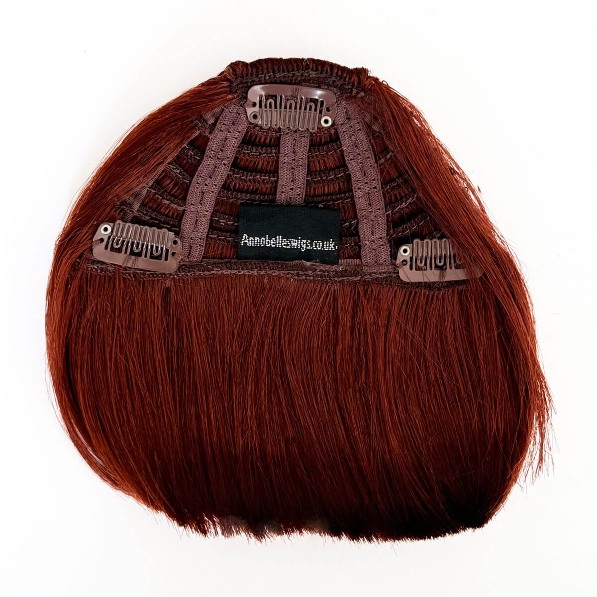 Brown hair extension with clip-in mechanism on a white background. Clip-in fringe hairpiece/clip-in bangs, thick, straight retro rockabilly style: Ida copper red 130