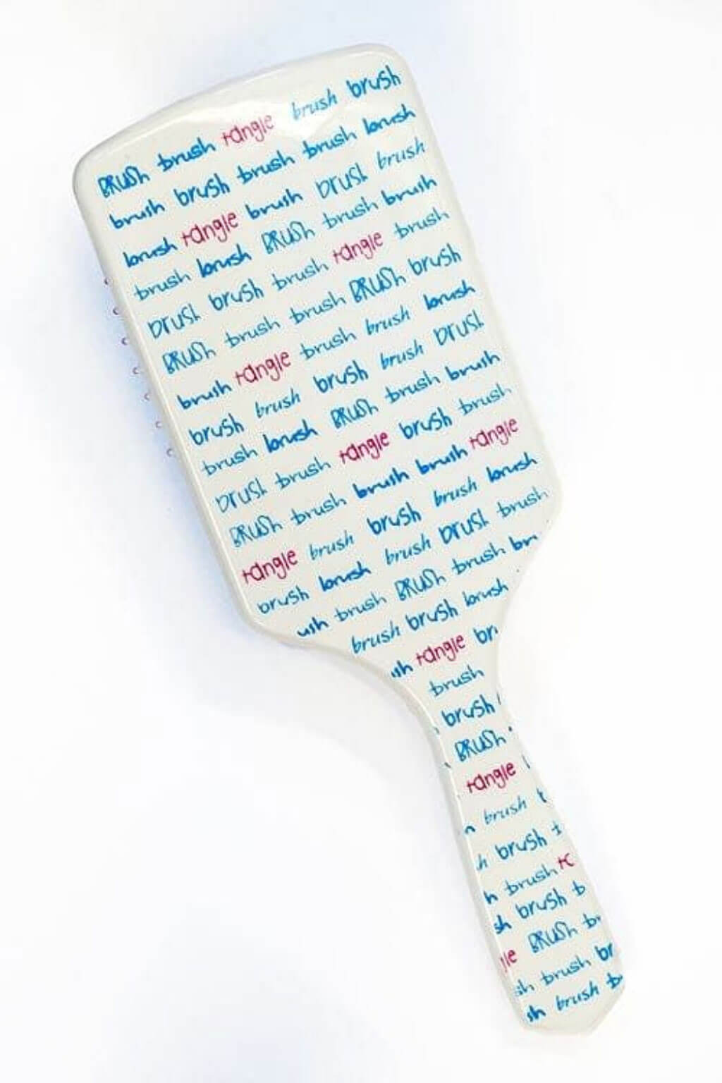 White paddle brush with text on a white background. Brush Brush Tangle' Wide Toothed Professional Hair Brush