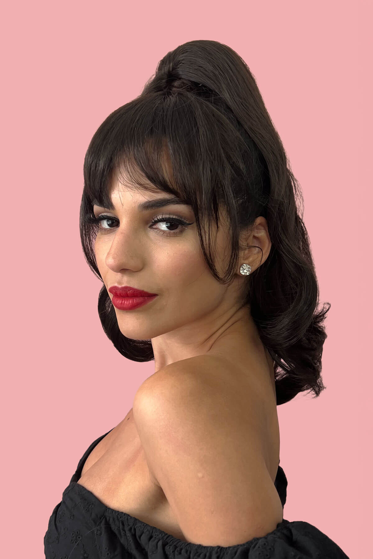 Woman with styled hair and red lipstick against a pink background. Clip in fringe hairpiece/clip-in bangs, gently feathered with face framing whisps: Delia black 1B