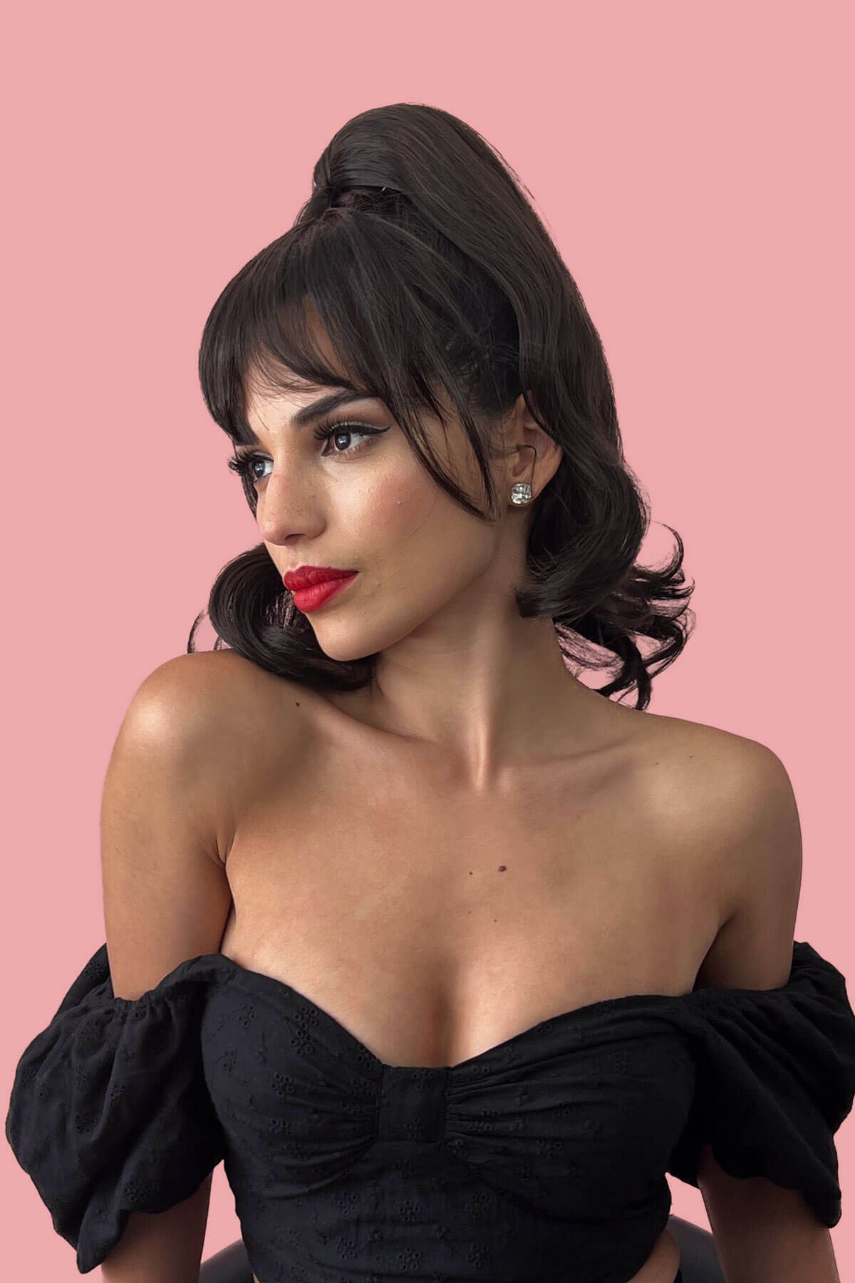 Woman wearing a black off-shoulder top against a pink background. Clip in fringe hairpiece/clip-in bangs, gently feathered with face framing whisps: Delia copper red 130