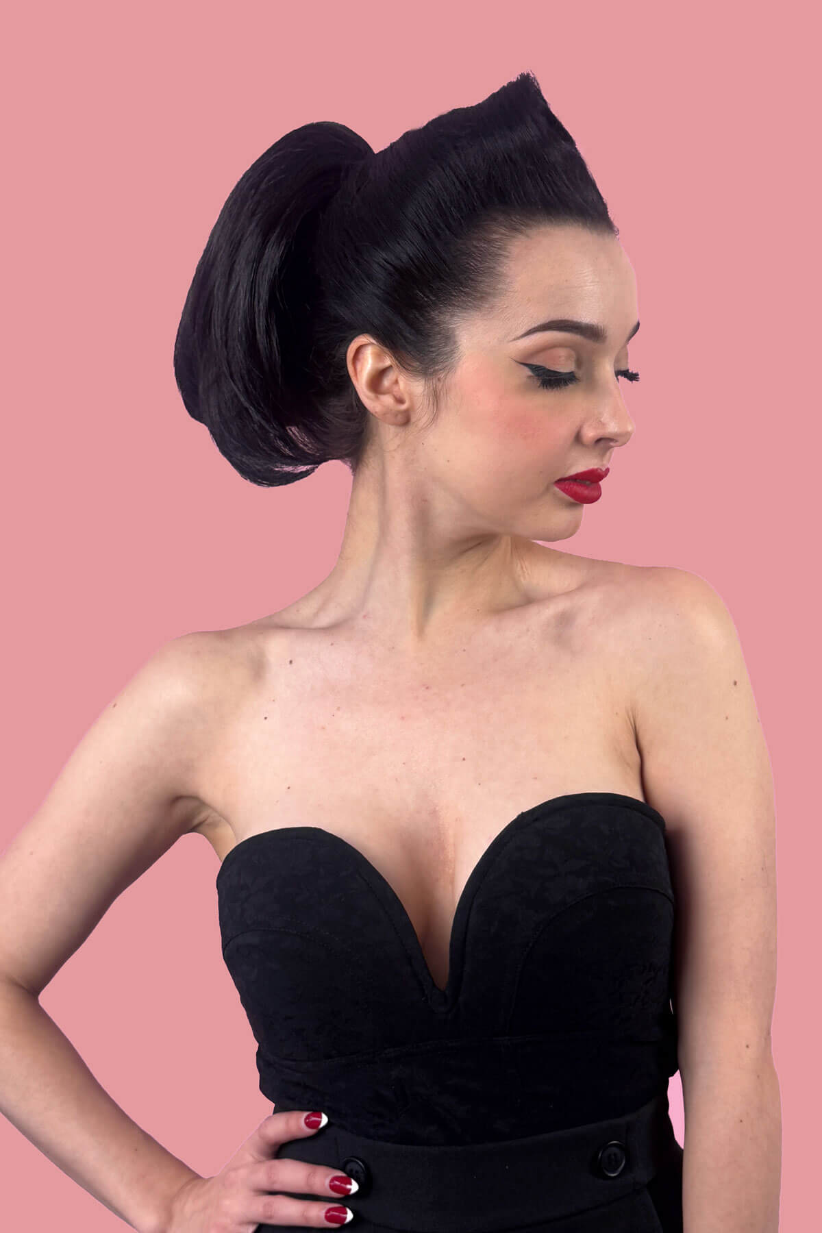 Woman with styled hair, with short ponytail against a pink background. Short beehive ponytail hairpiece: Sherri black 1B
