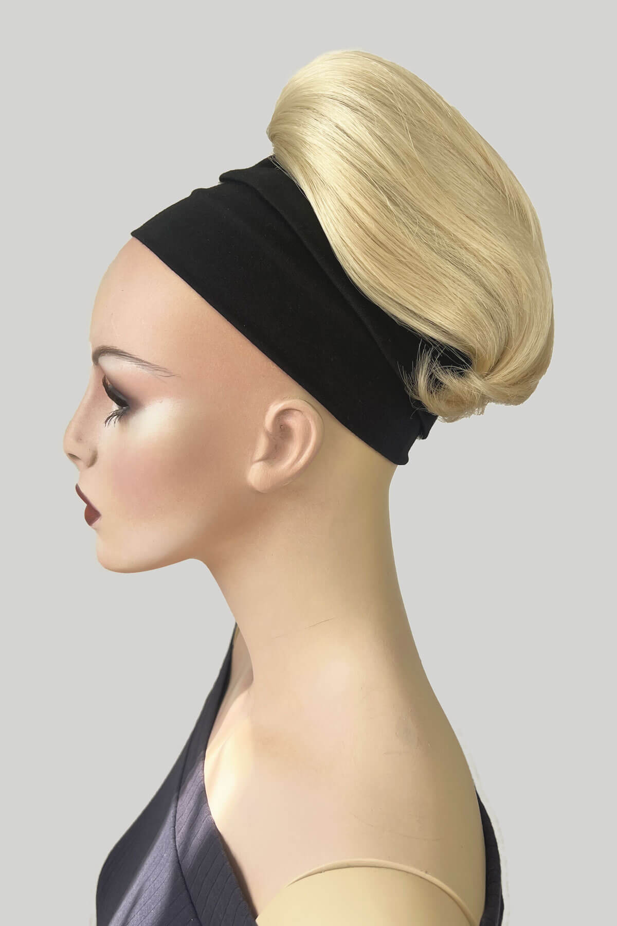 Mannequin with blonde hair piece. A woman wearing a green top and a beehive ponytail hairpiece in a soft blonde color. blonde 613