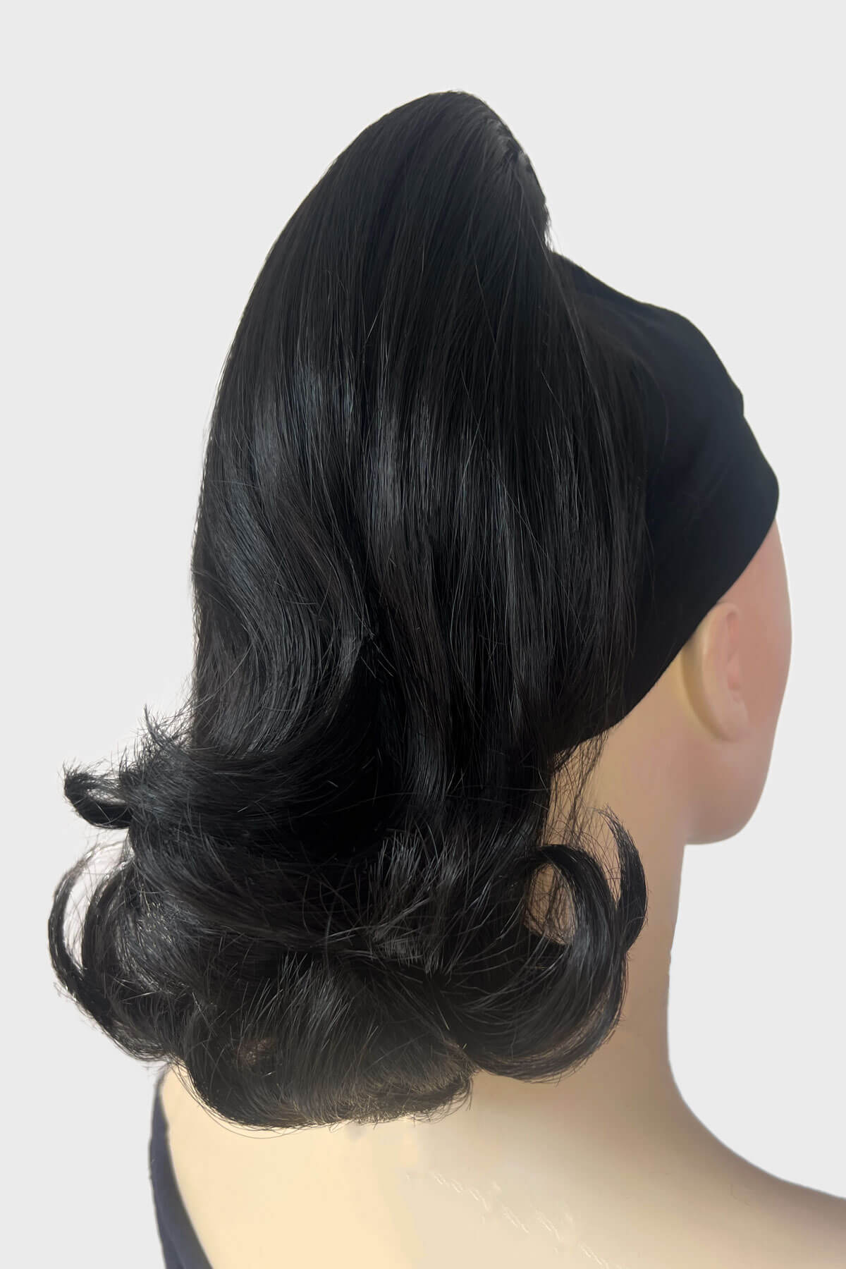 Black hair bun on a mannequin head against a white background. Ponytail hairpiece, shoulder length with flick/flip, retro 1960s style: Ariana black 1B