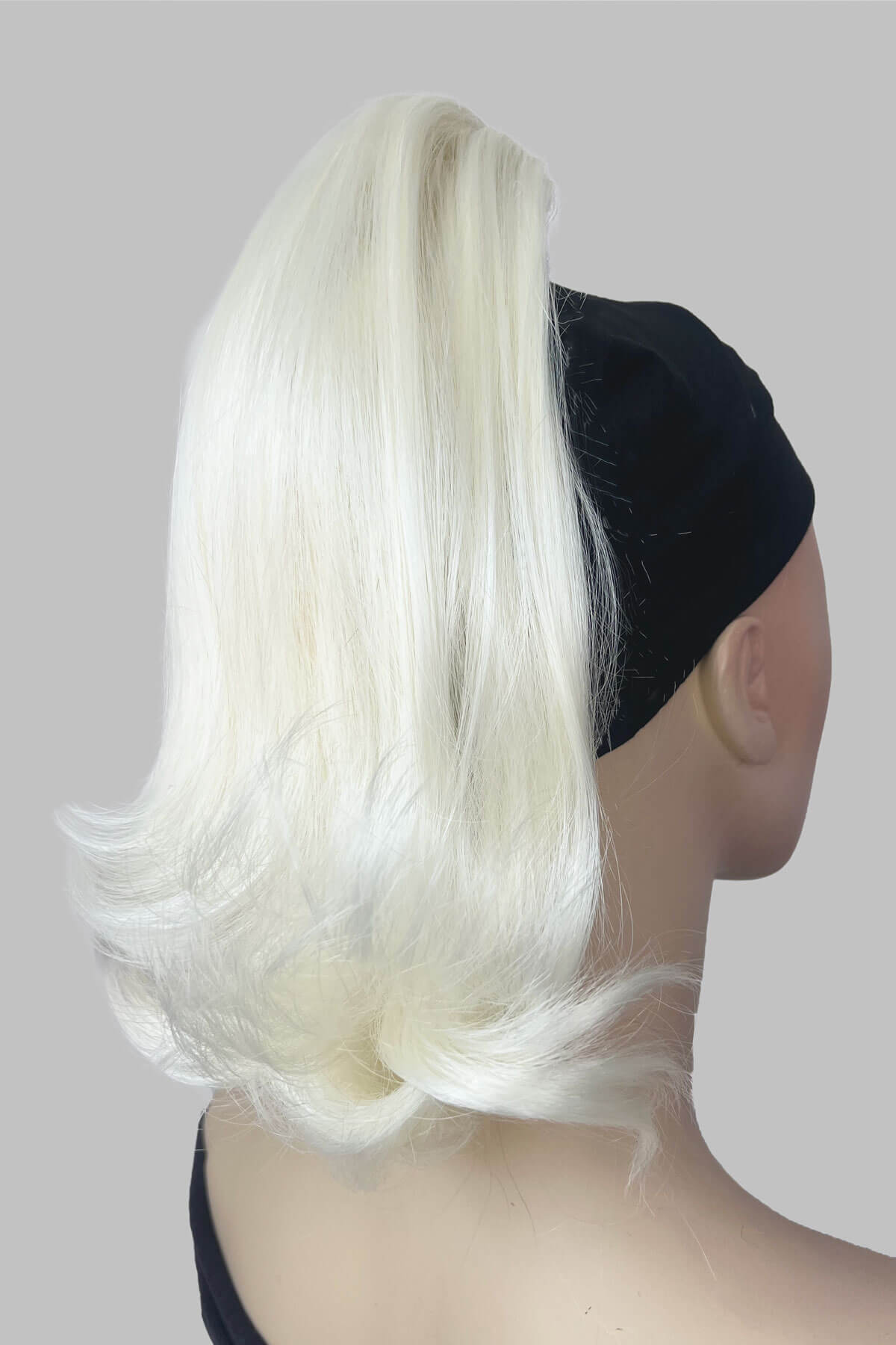 Mannequin head with white hair and a black headband on a gray background. Ponytail hairpiece, shoulder length with flick/flip, retro 1960s style: Ariana Platinum blonde 1001