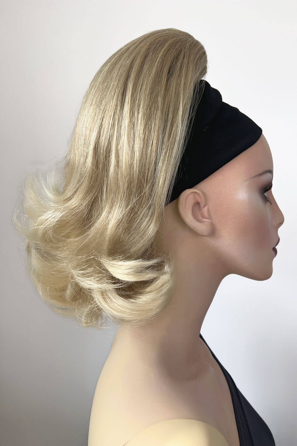 Mannequin head with blonde wig and black headband on a white background. Ponytail hairpiece, shoulder length with flick/flip, retro 1960s style: Ariana blonde 613T24