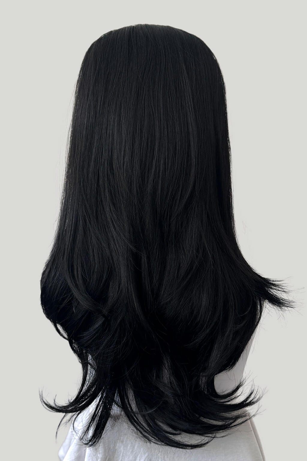 Black wig on a mannequin head against a white background. 1960s style hair, high crown long straight and layered half wig: Juliette black 1b