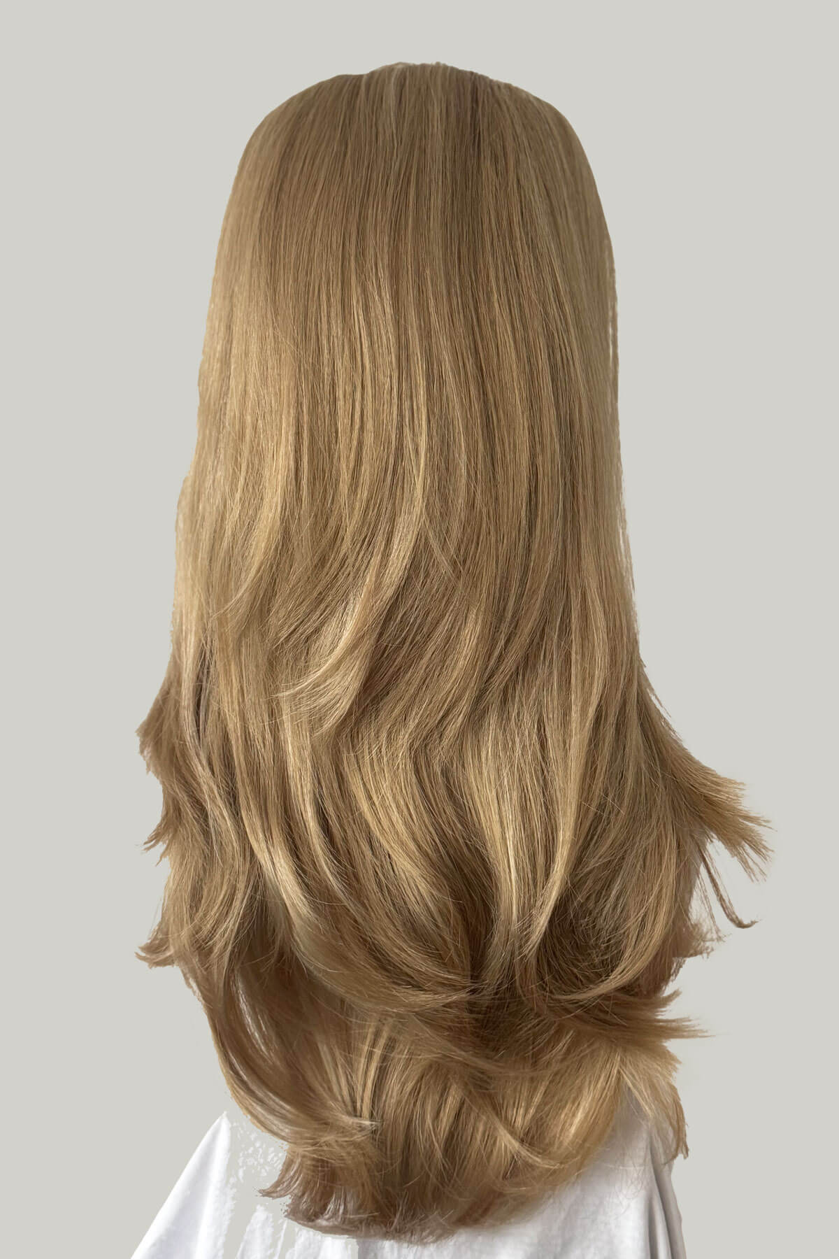 Blonde wig, from behind, with wavy hair on a neutral background. 1960s style hair, high crown long straight and layered half wig: Juliette 24H613