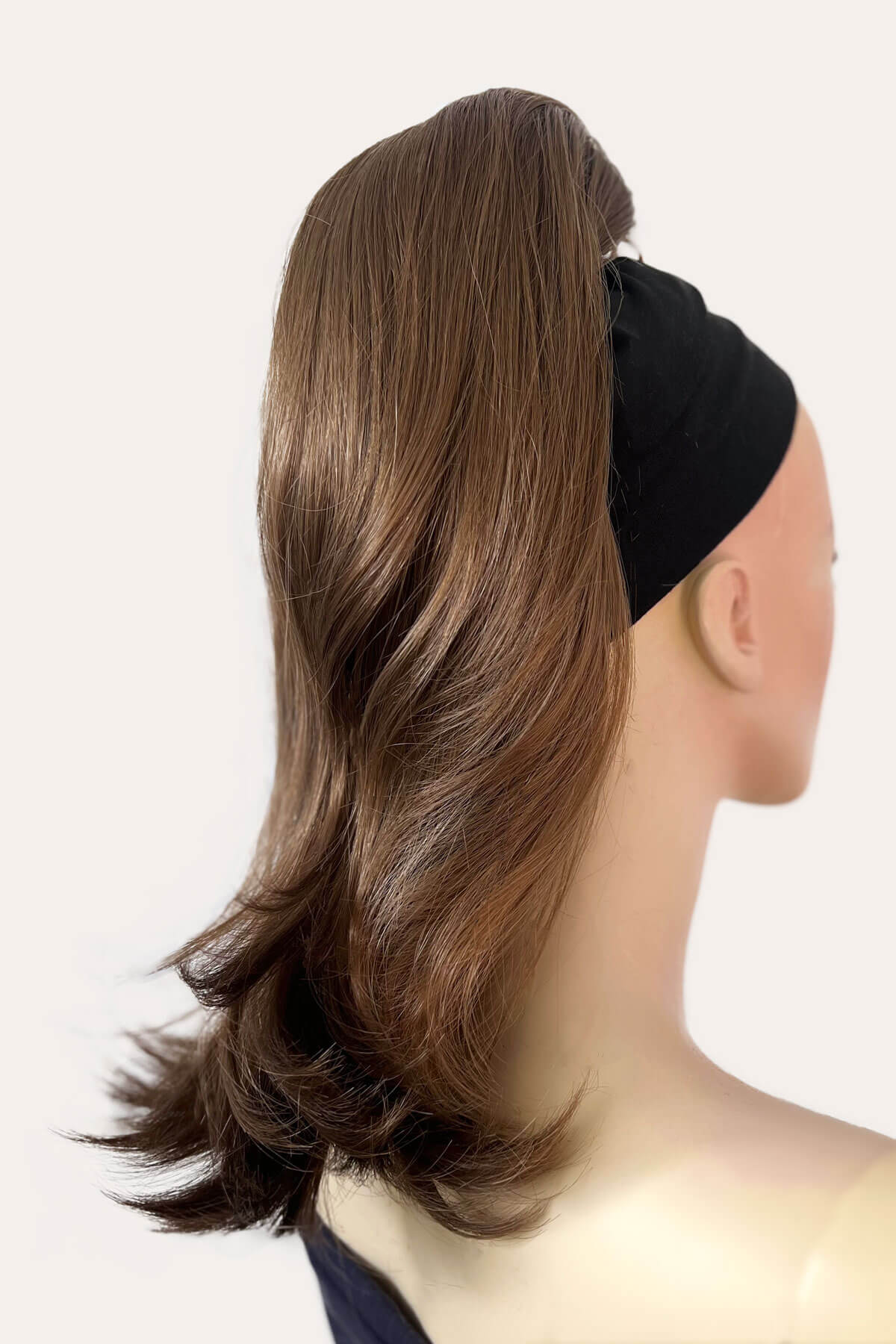 Mannequin head with brown hair styled in a ponytail and black headband on a white background