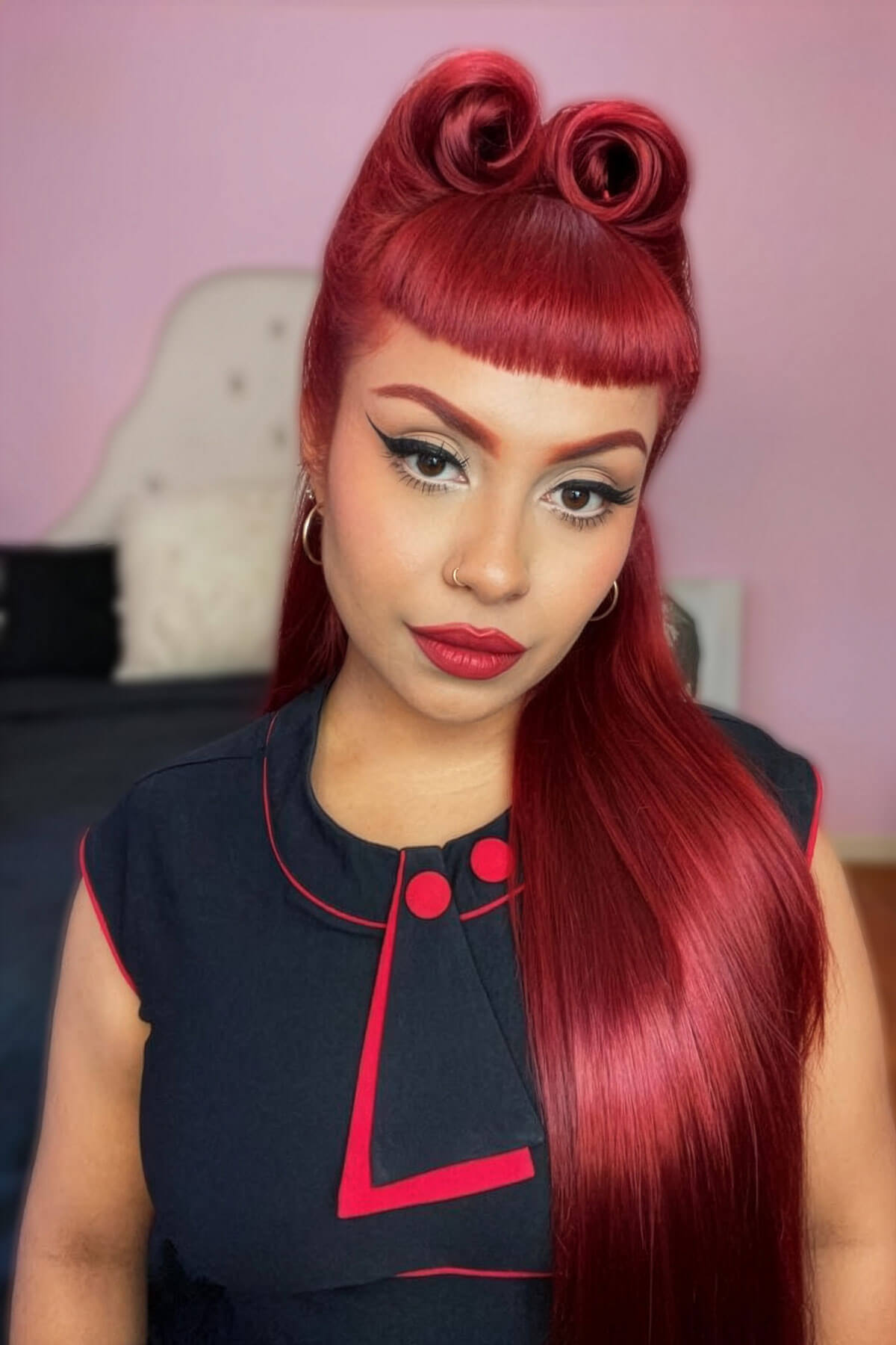 Woman with red hair styled in two victory rolls wearing a black outfit with red accents. Victory roll kit: Ingrid - cherry red