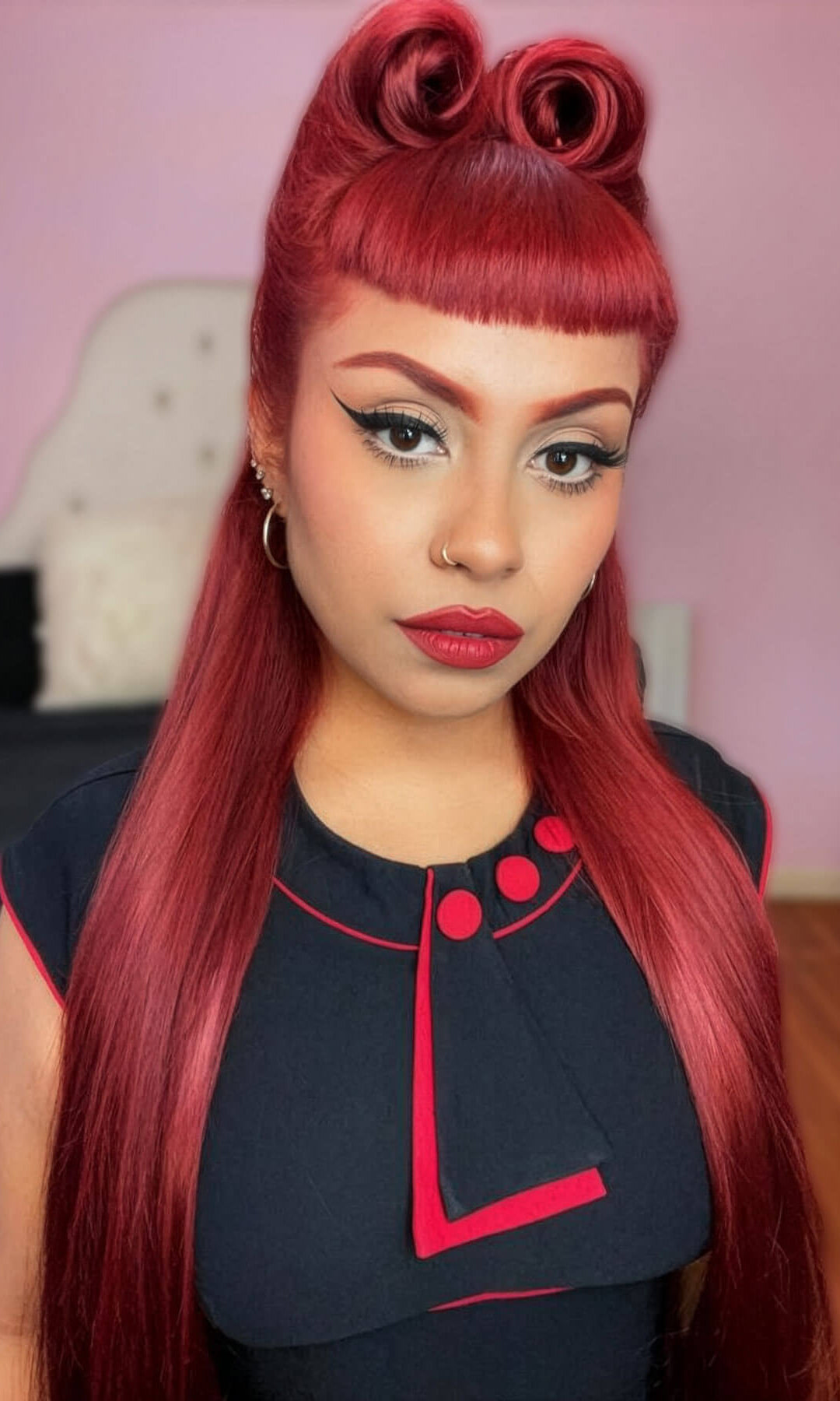 Woman with red hair styled in two victory rolls wearing a black outfit with red accents. Victory roll kit: Ingrid - cherry red