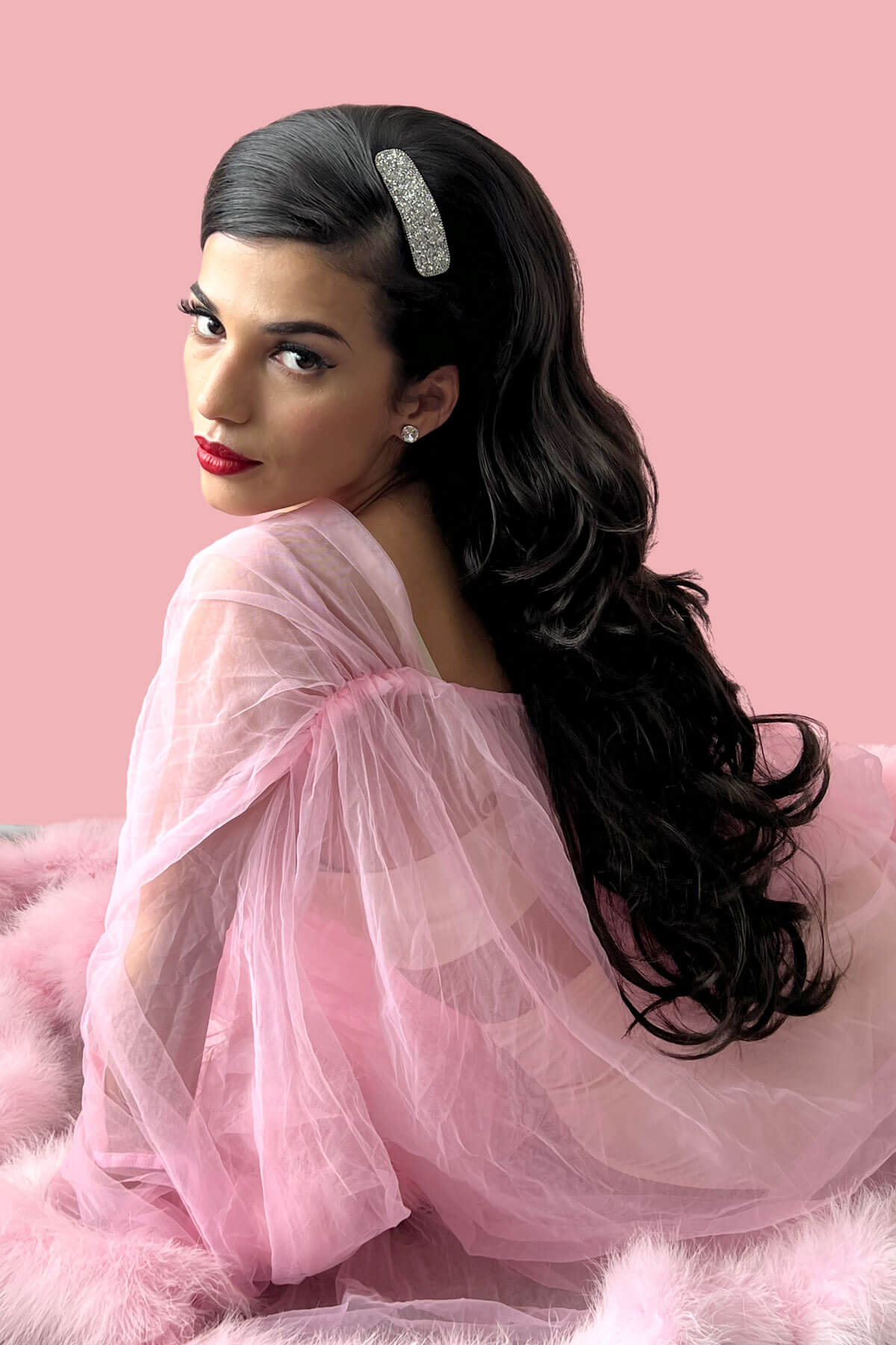 Woman with long dark hair and red lipstick wearing a pink dress against a pink background. High crown long layered half wig and volume ring Helena brown 4