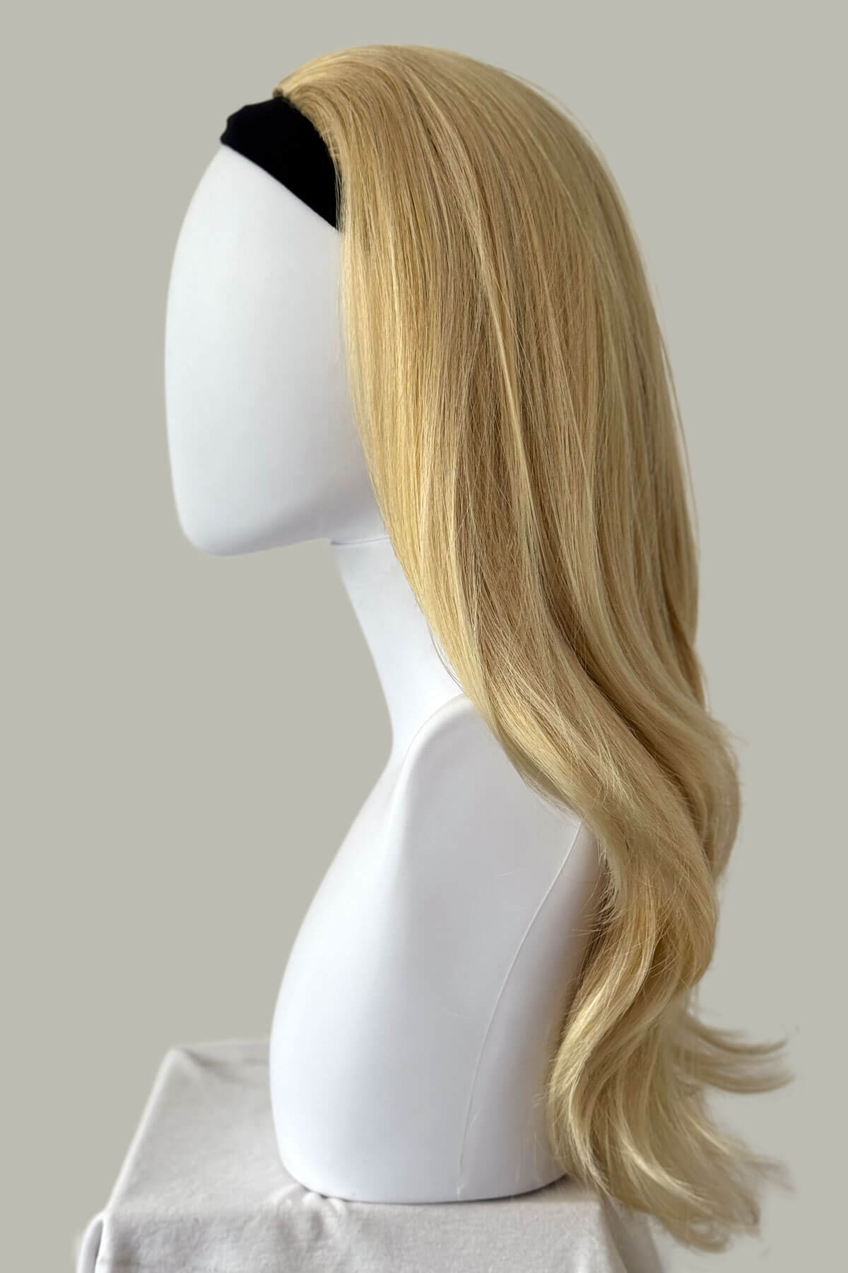 Blonde wig on a mannequin head against a plain background. Straight blonde half wig hairpiece (3/4 wig), layered: Autumn light ash blonde 24BT613