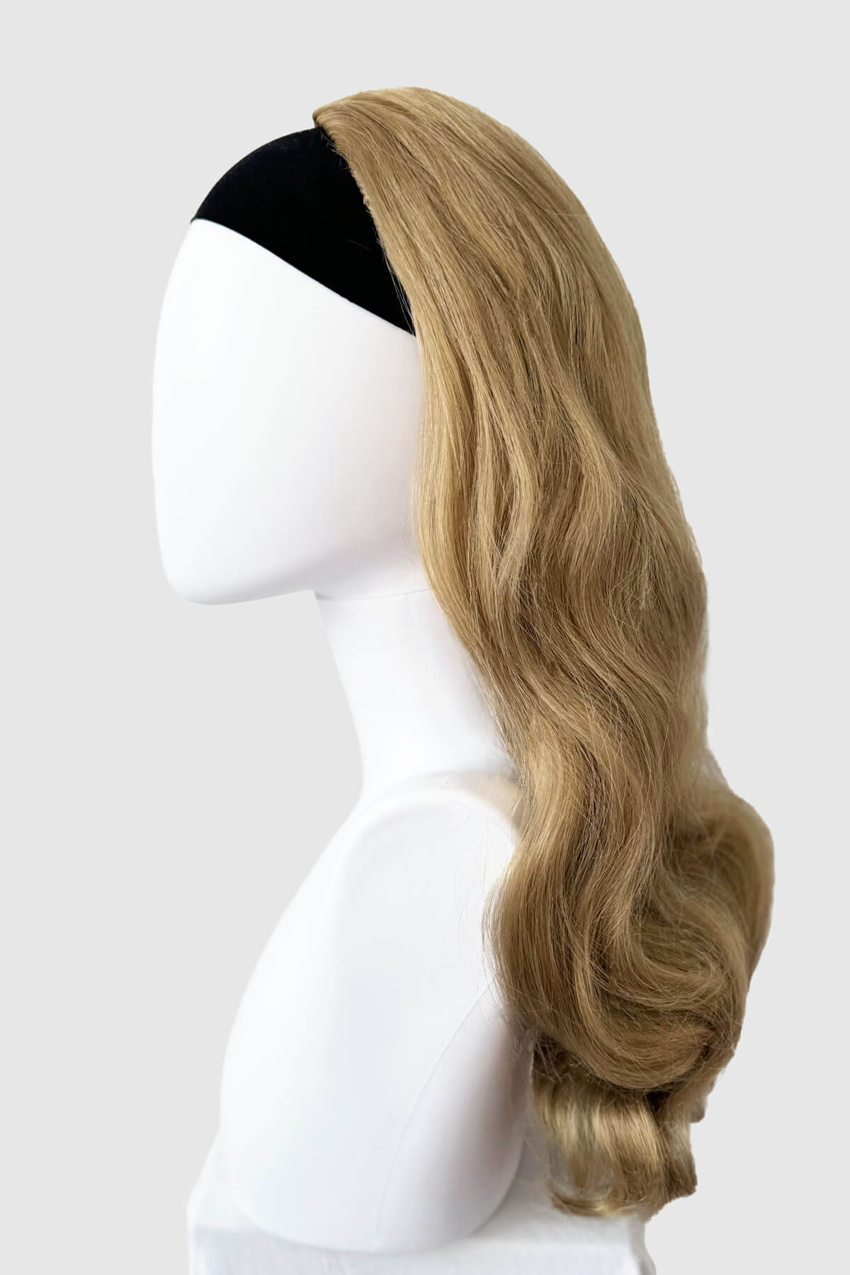 Blonde wig on a mannequin head against a white background. 1950s style half wig hairpiece with beautiful waves: Morgana blonde 24H613