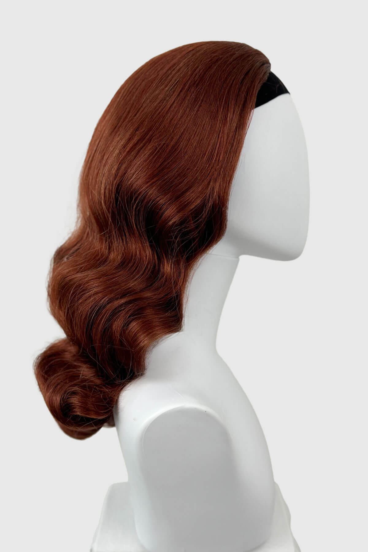 Copper red wig on a white mannequin head against a white background. 1950s style half wig hairpiece with beautiful waves: Morgana copper red 130