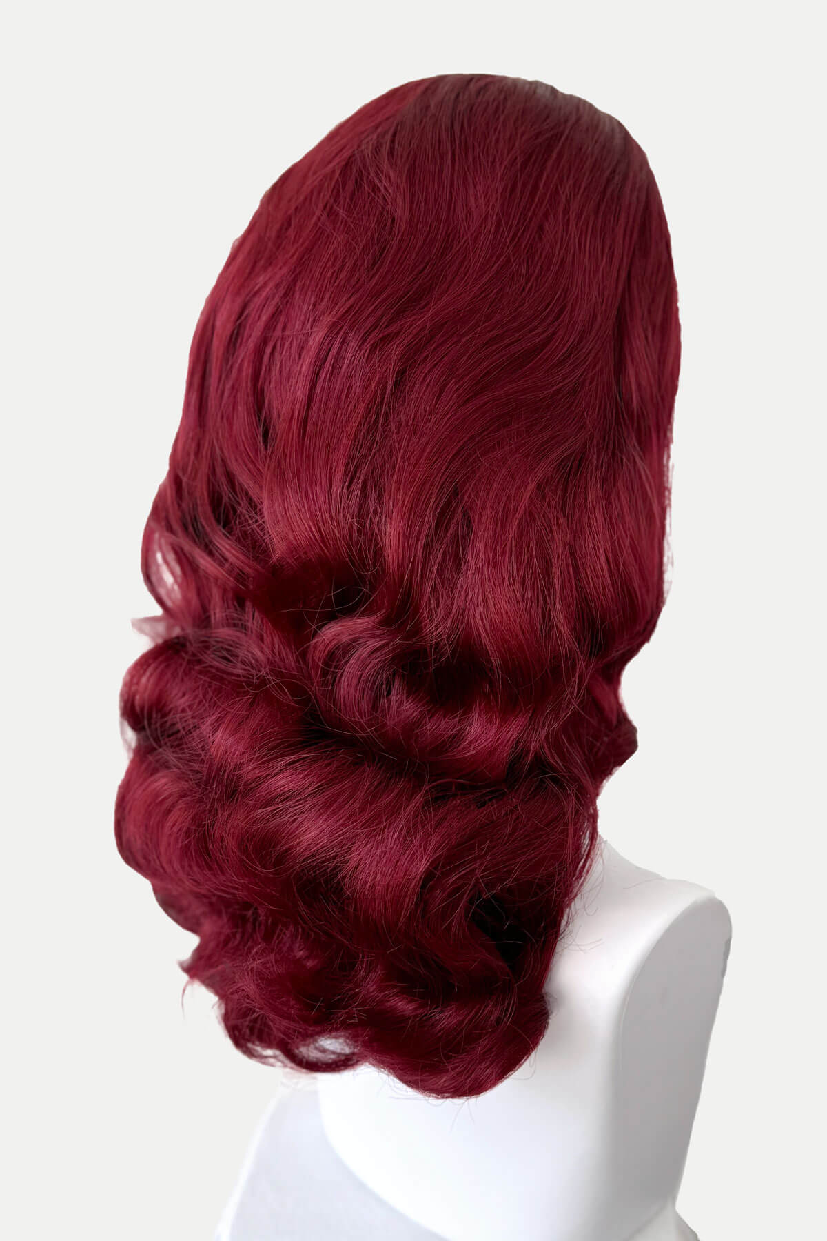 Red wig on a white mannequin head against a white background. 1950s style half wig hairpiece with beautiful waves: Morgana red 39