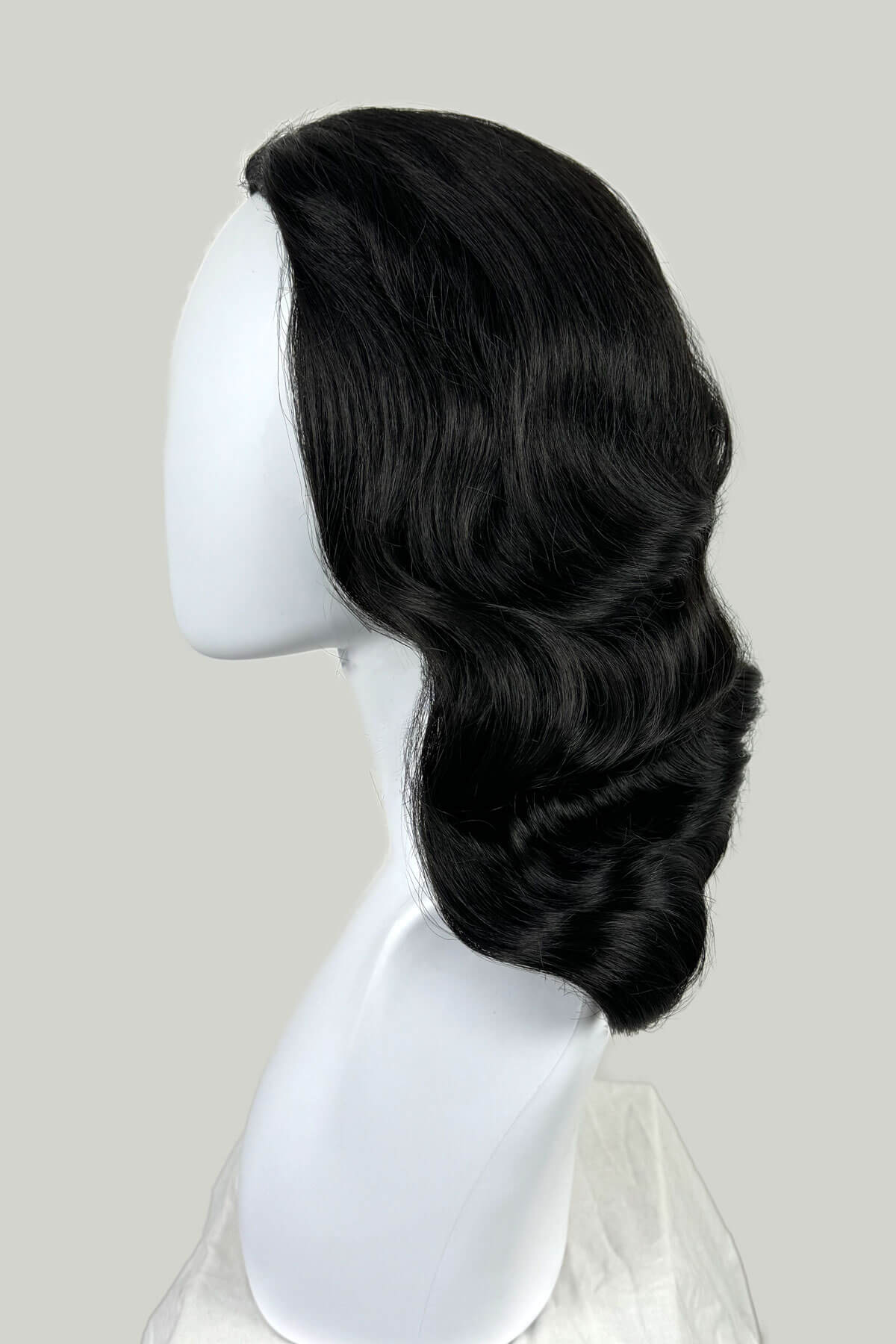Black wig on a white mannequin head against a light gray background. 1950s style half wig hairpiece with deep finger waves: Deborah black 1B