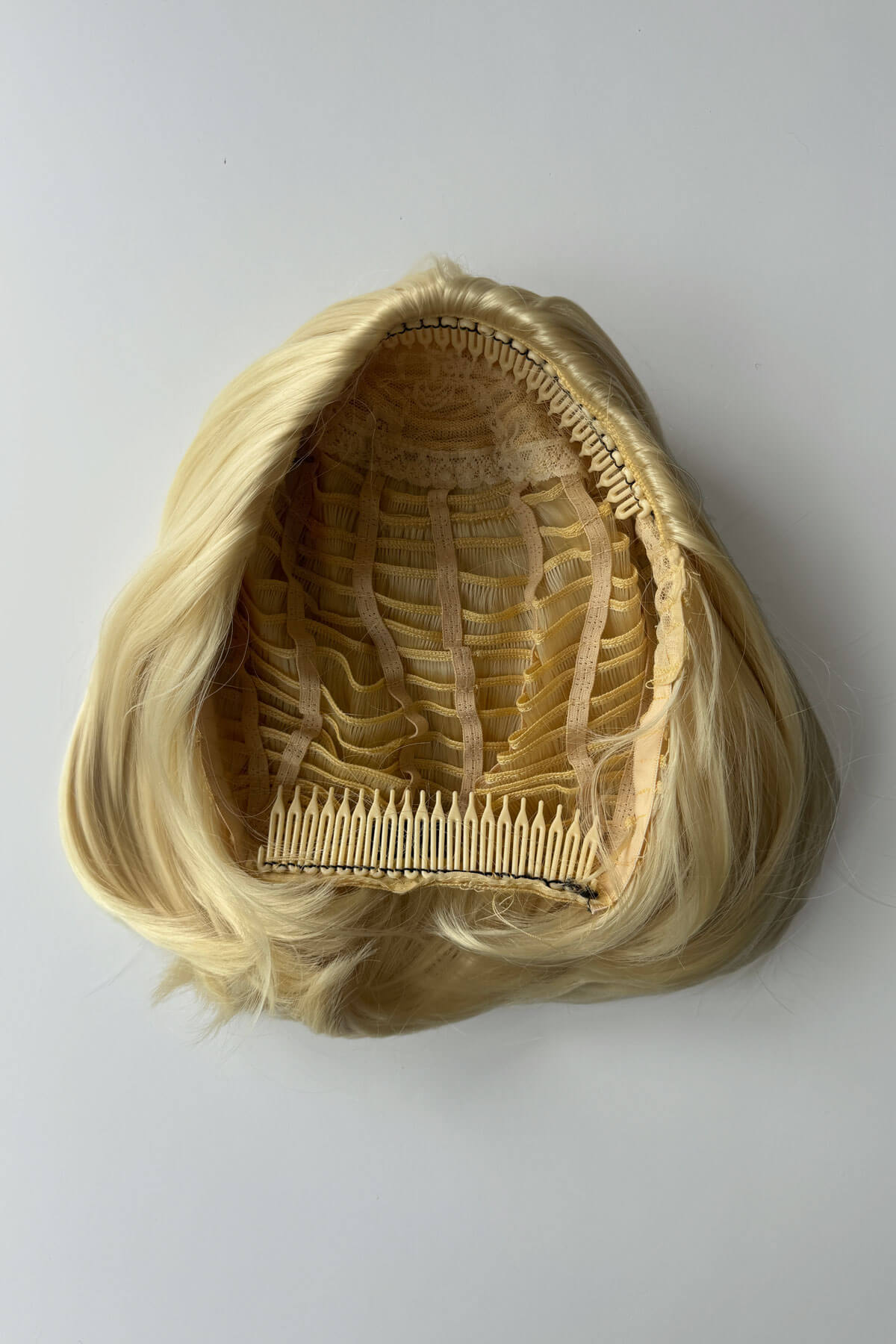 Blonde half wig with a comb on a grey background. Bob half wig hairpiece, heat styleable - Amelie blonde 613
