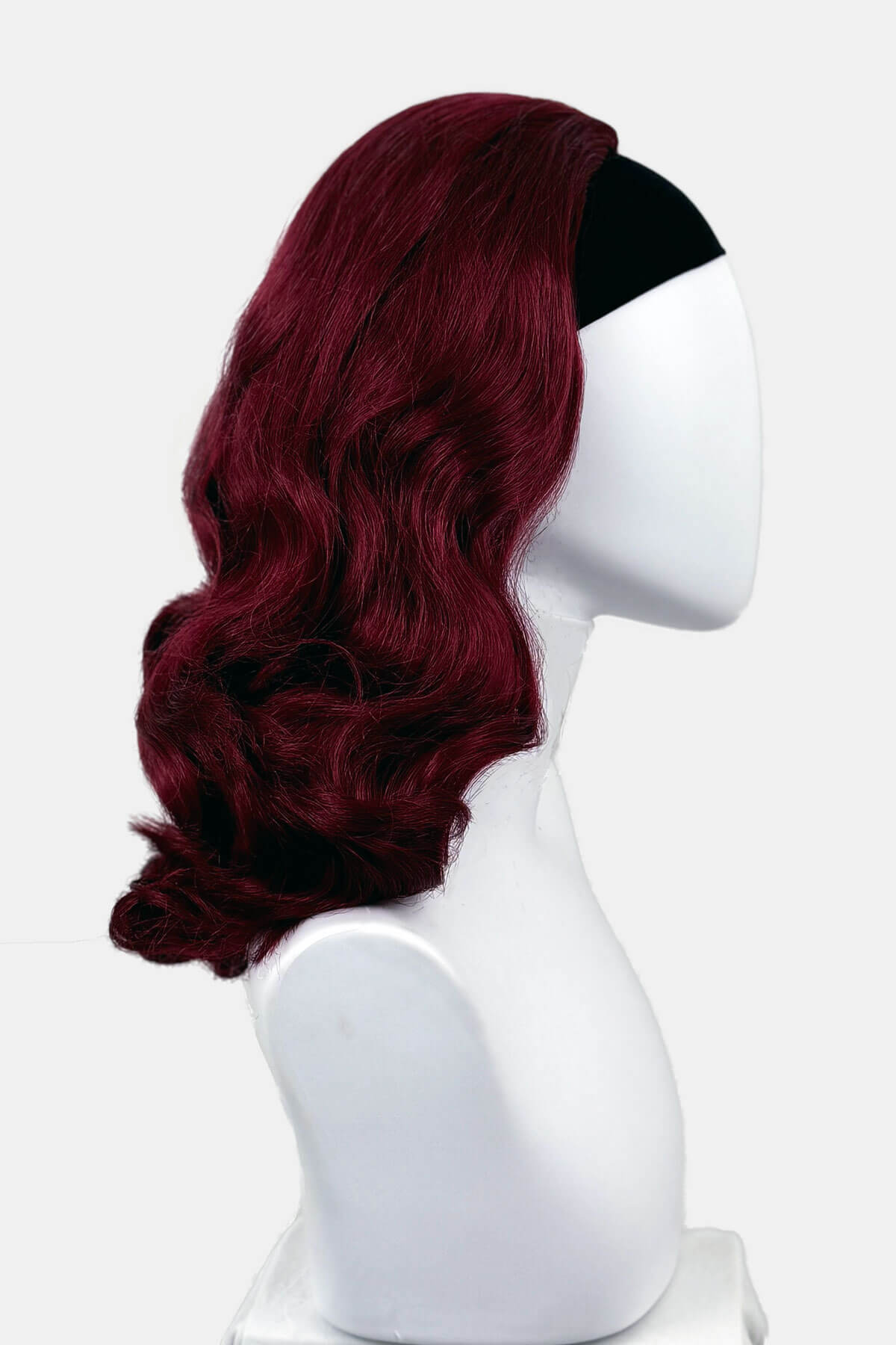Red wig on a white mannequin head against a white background viewed from the side. 1950s style shoulder length half wig hairpiece with beautiful vintage waves: Onyx cherry red 39