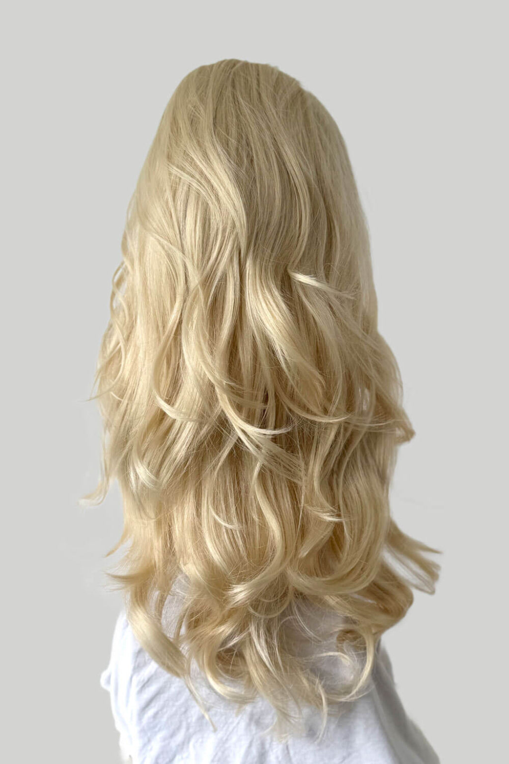 Blonde wig with wavy hair on a plain background. High crown long, wavy half wig and volume ring: Bardot blonde 613