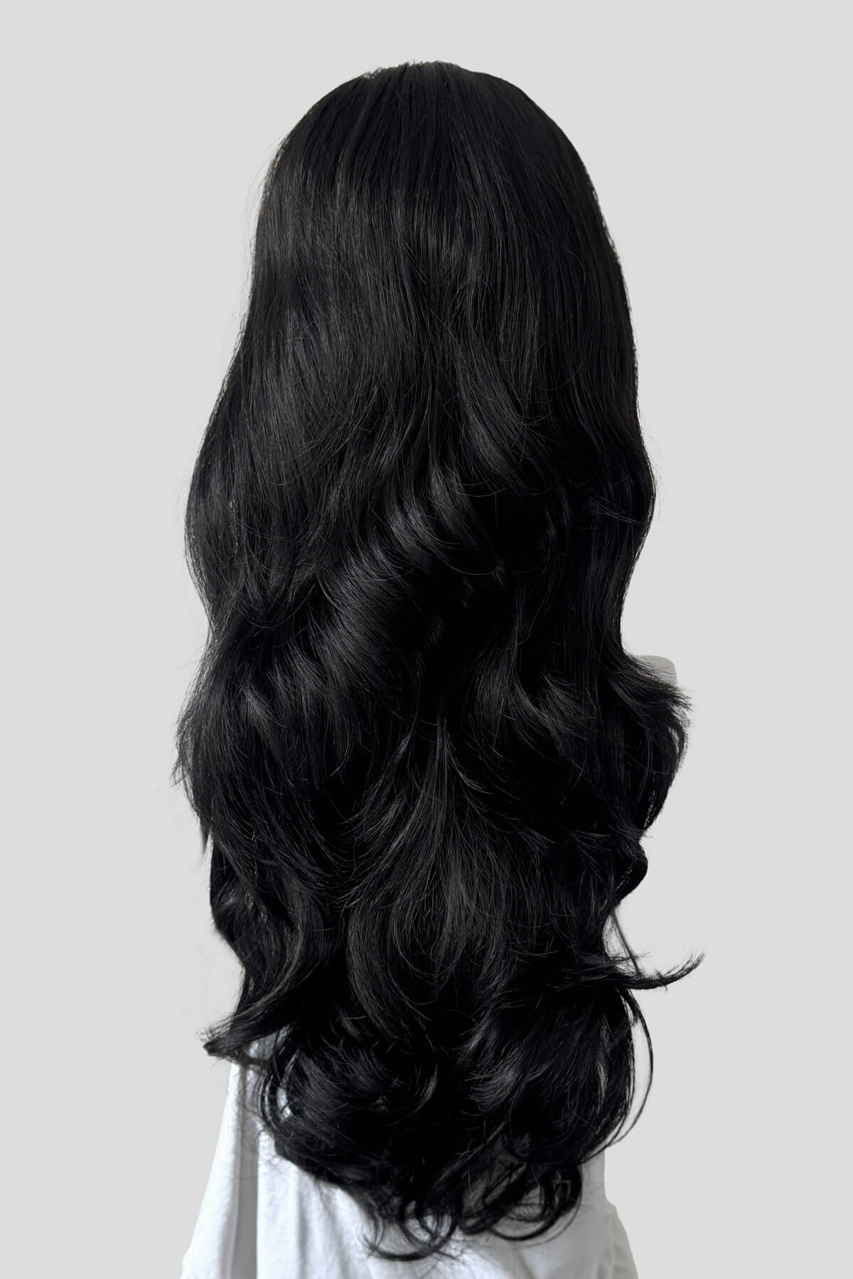 Long, wavy black wig shown from the back against a light grey background. Half wig with volume booster/height booster: Corrine black 1B