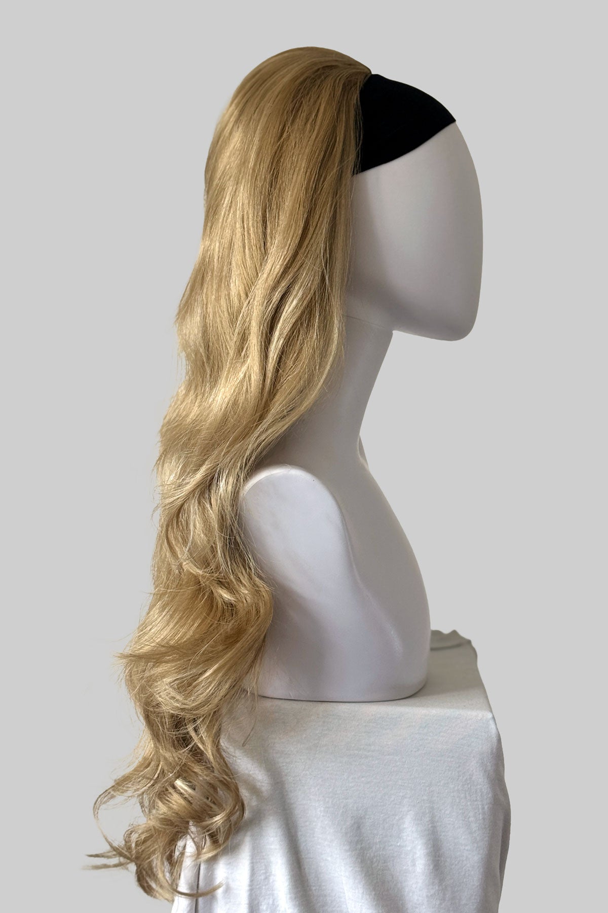 Long wavy blonde wig with a black top band, displayed on a white mannequin head against a light background. Corrine - Bouncy Blowout style with Volume Booster Half Wig blonde 24H613