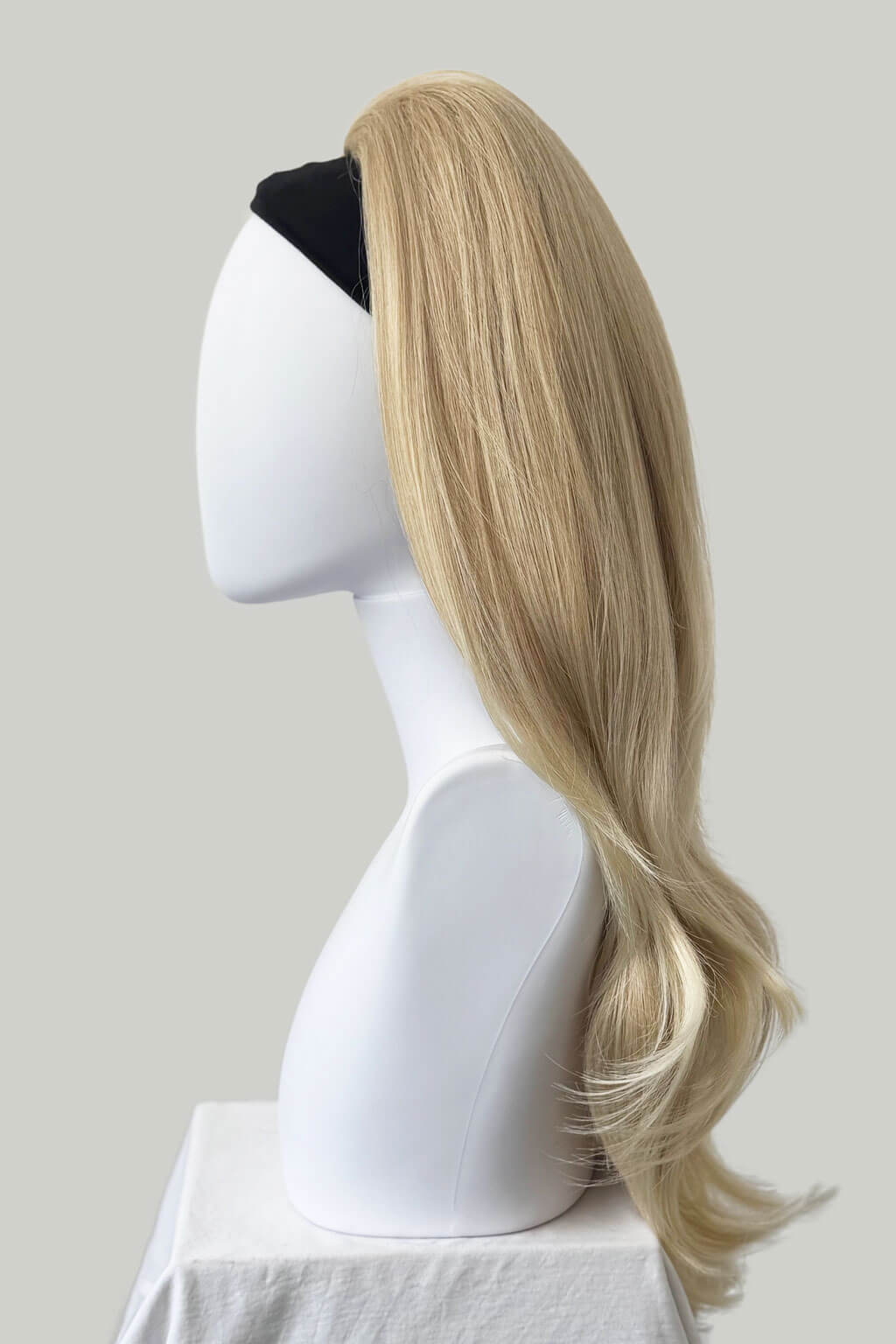 Blonde wig on a mannequin head against a plain background. 1960s style hair, high crown long straight and layered half wig: Juliette blonde 613T24