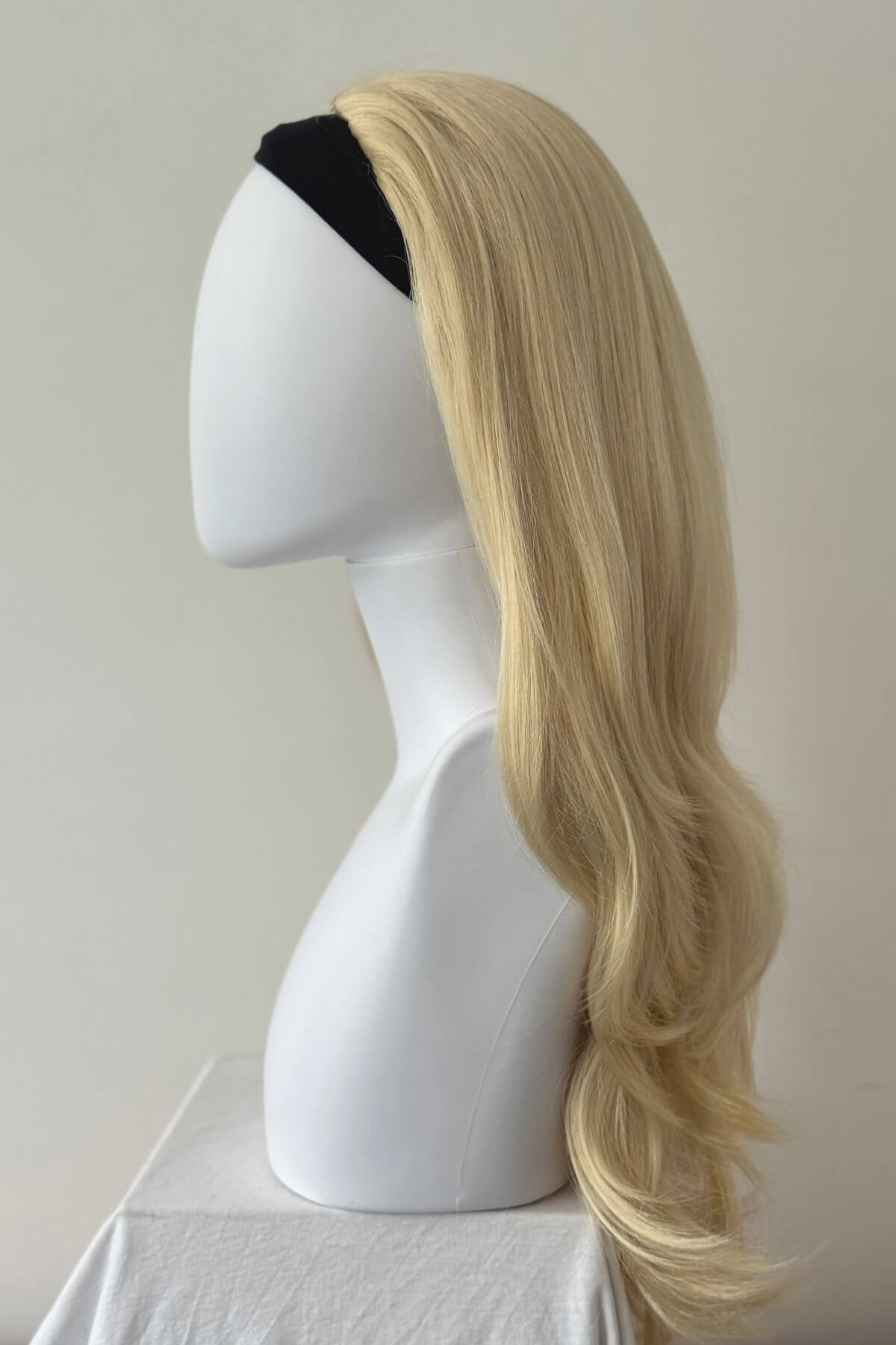 Blonde wig on a mannequin head against a plain background. Straight blonde half wig hairpiece (3/4 wig), layered: Autumn champagne blonde 613