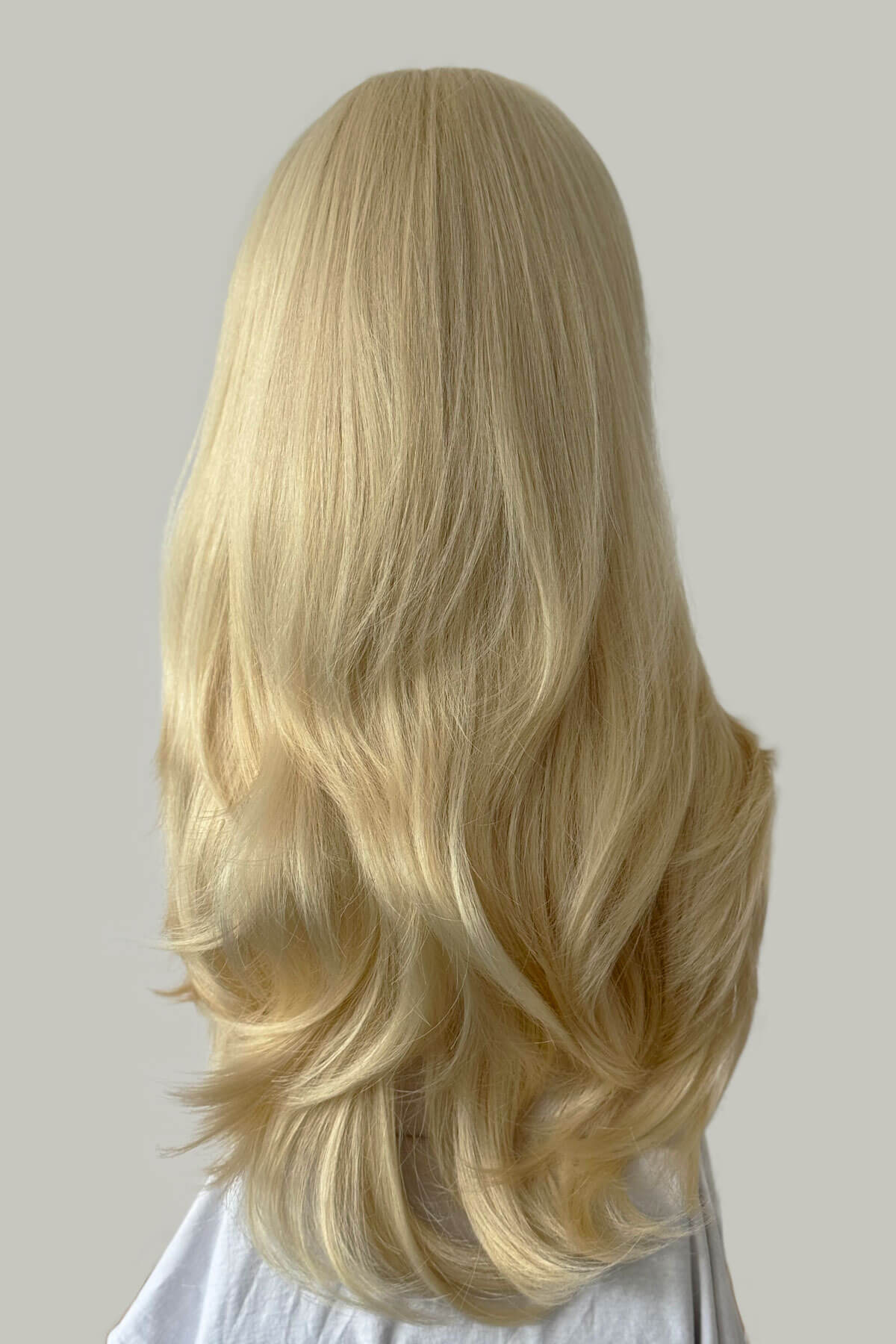 Blonde wig with wavy hair on a neutral background. Straight blonde half wig hairpiece (3/4 wig), layered: Autumn champagne blonde 613