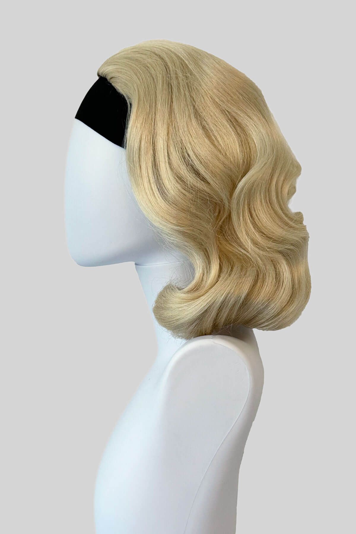 Mannequin with vintage style wig with marcel waves on it, from the side. 1940s style half wig hairpiece with beautiful marcel waves: Virginia creamy blonde 613