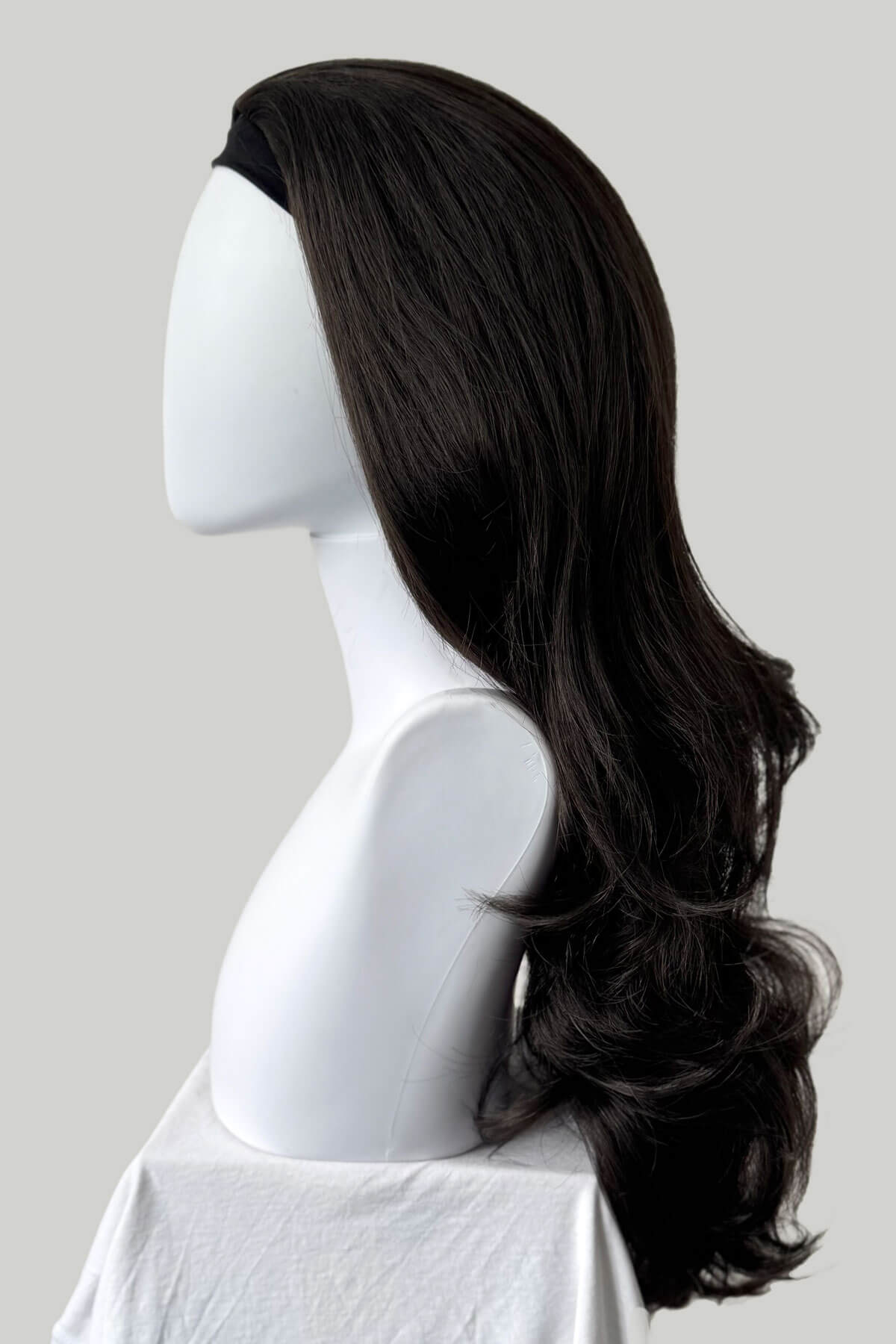 Black wig on a mannequin head against a plain background. Brown half wig hairpiece, full, long with gentle waves: Taya dark brown 4