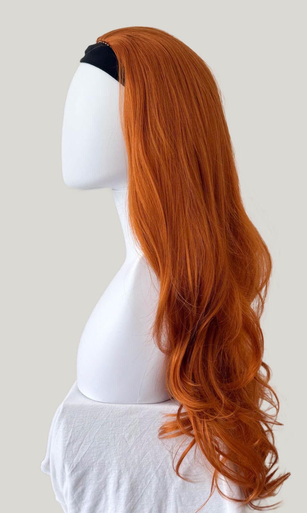 Ginger wig on a mannequin head against a plain background. Ginger half wig (3/4 hairpiece) with long waves: Keegan
