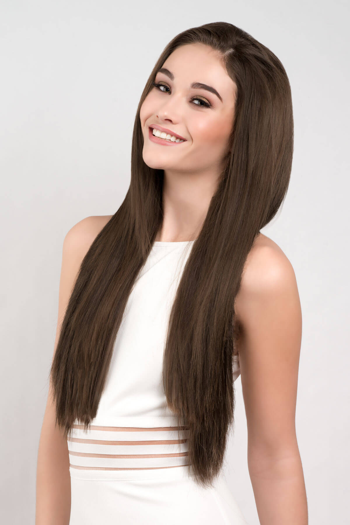 Woman with long brown hair wearing a white top on a light gray background. Straight brown half wig hairpiece extension, long: Faye chestnut brown 8