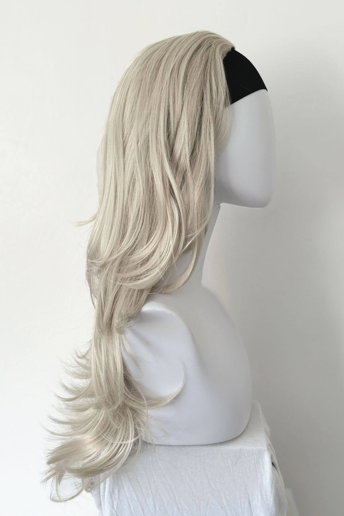 Blonde wig on a mannequin head against a white background. Silver half wig hairpiece (3/4 wig), loose curls: Tahlia