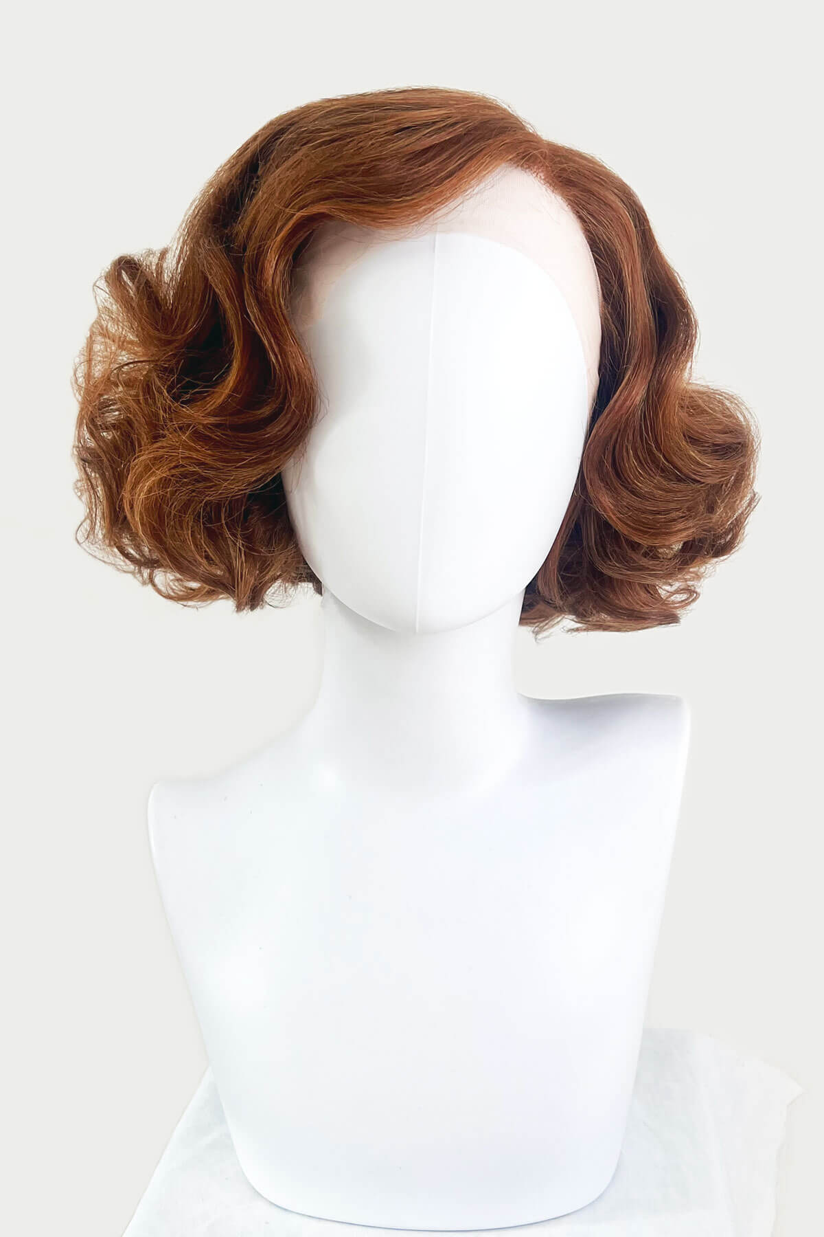 Brown wig on a mannequin head against a white background. Auburn pinup wig, lace front, vintage style: Clementine