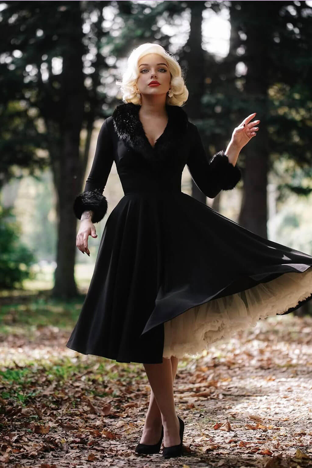 Woman in a black coat with fur collar standing in a forest. Blonde pinup wig, lace front, vintage style: Marilyn white blonde 1001