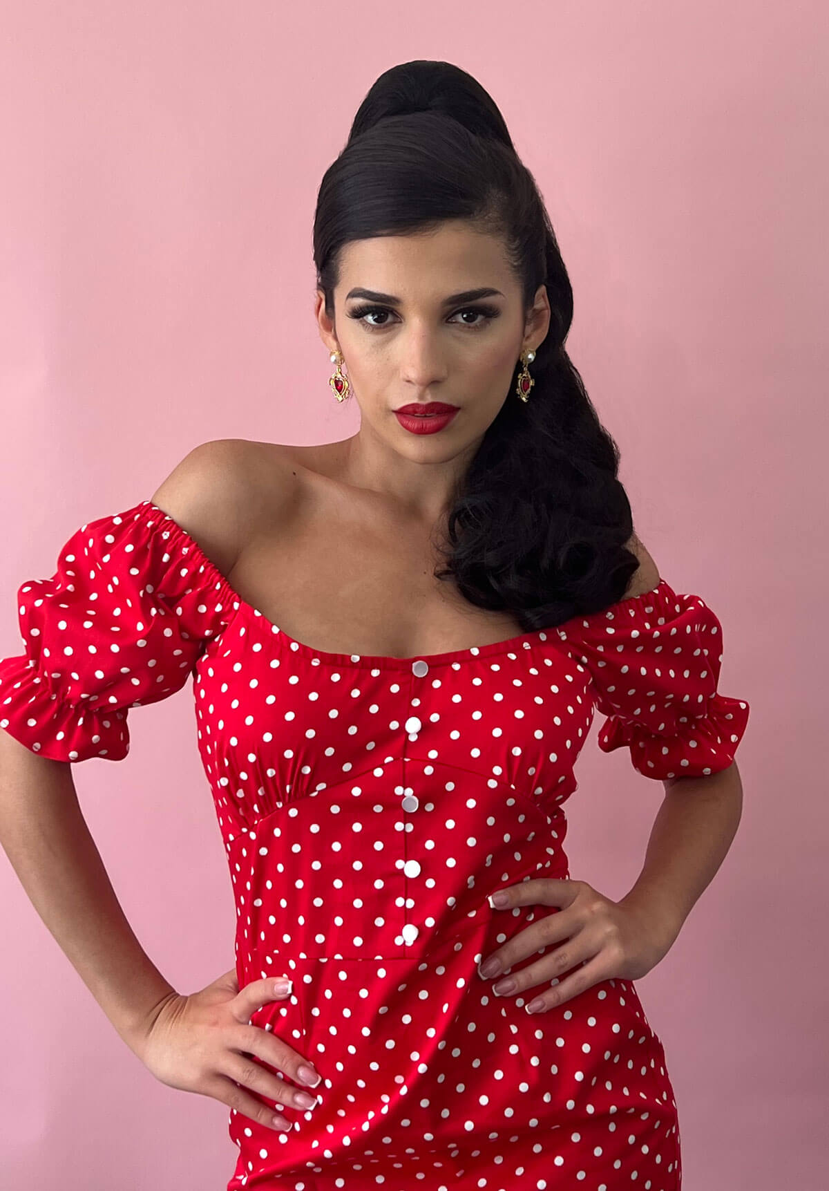 Woman wearing a red polka dot dress against a pink background. Retro style ponytail hairpiece, long with vintage waves: Arabella dark brown 4