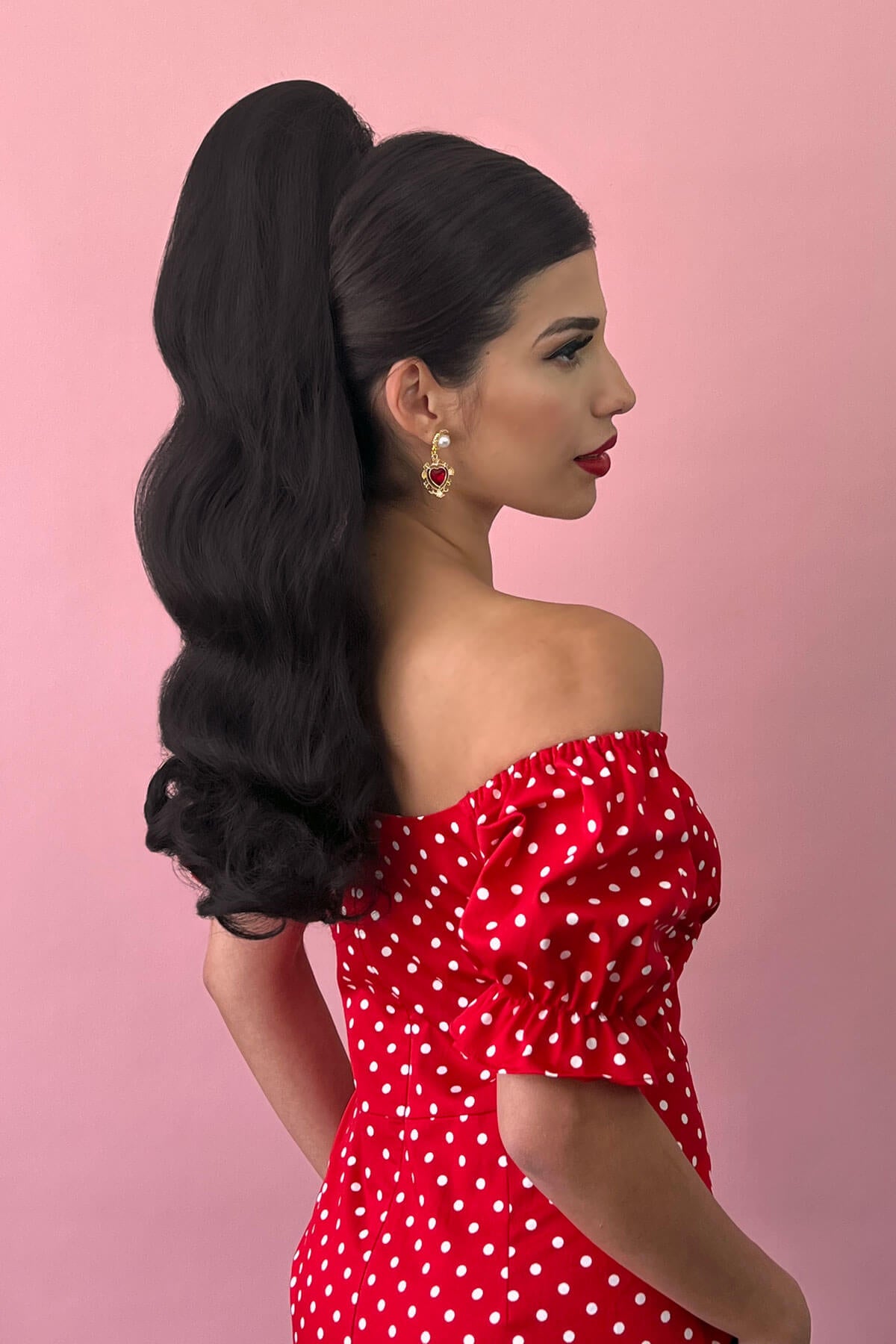 Woman in a red polka dot dress with a pink background. Retro style ponytail hairpiece, long with vintage waves: Arabella dark chocolate brown 6