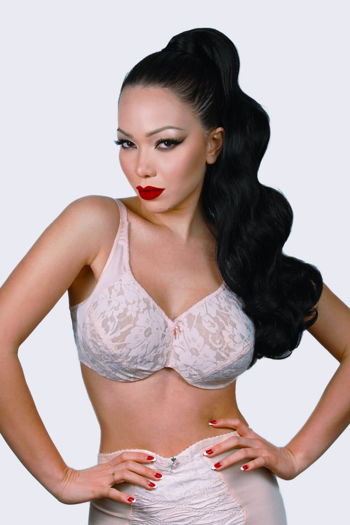 Woman wearing a white lace bra and panties set against a light gray background. Long ponytail with vintage waves: Kitrysha black 1b