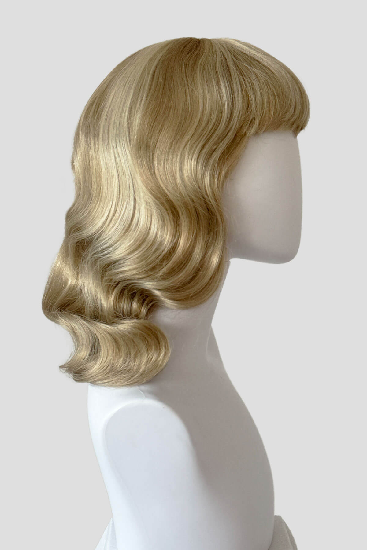 Blonde wig on a mannequin head against a white background. Blonde pinup wig with long finger waves and a short fringe: Cora Blonde 24H613