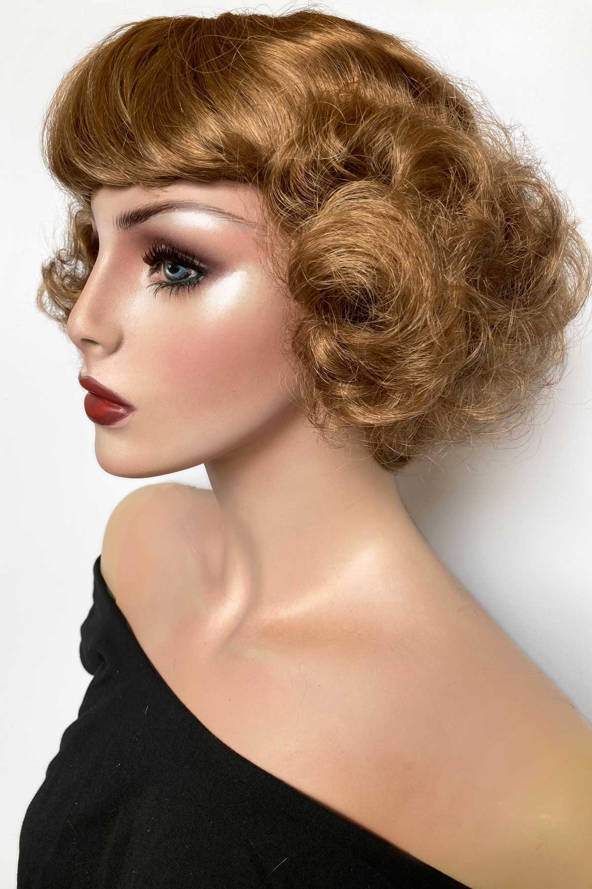 Woman with styled hair and makeup on a white background. A short brown vintage style wig with waves: Rita 12-27
