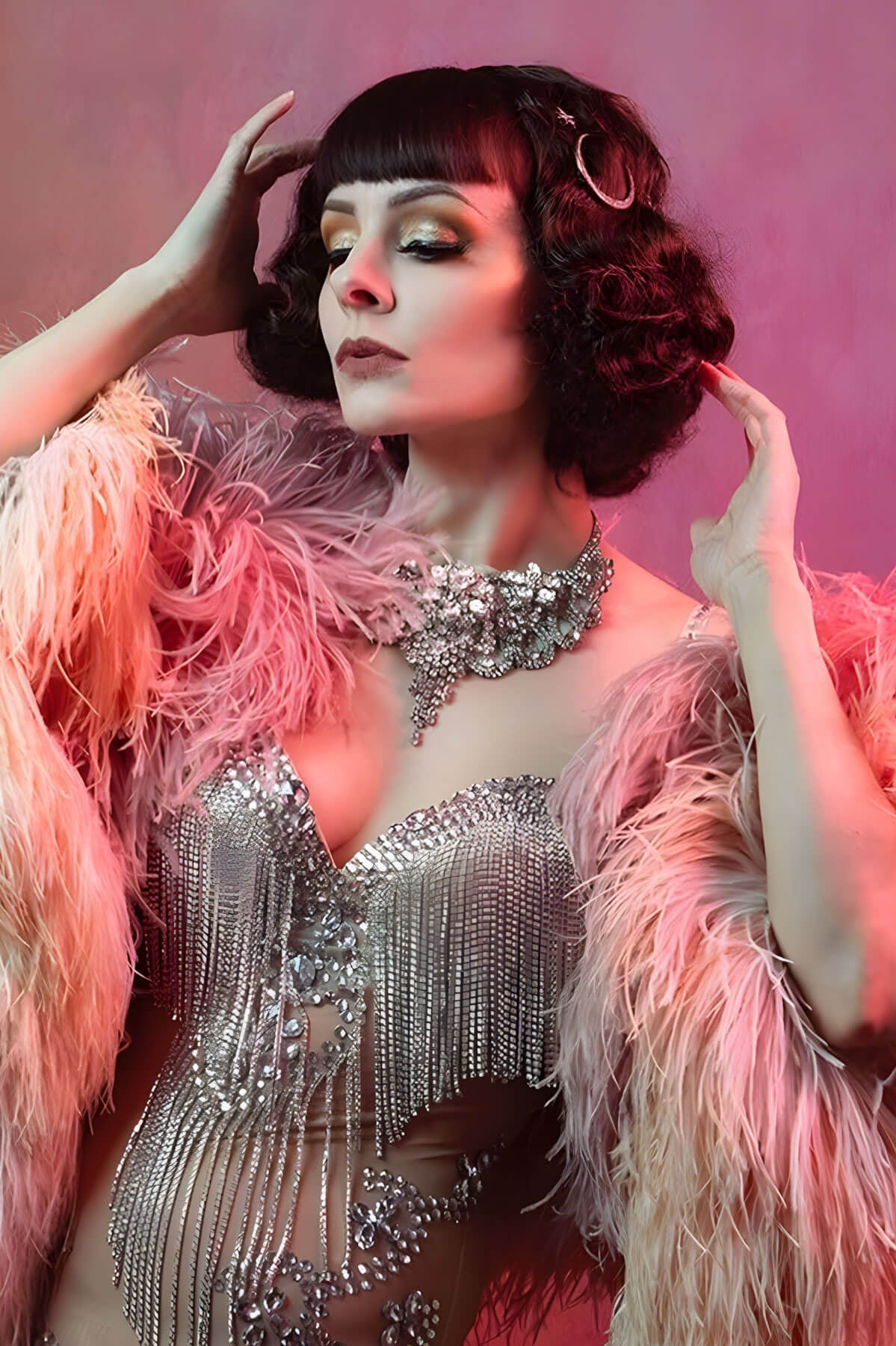 Woman in a glamorous outfit with a feathered boa against a pink background. A short brown vintage style wig with waves: Rita chestnut brown 8