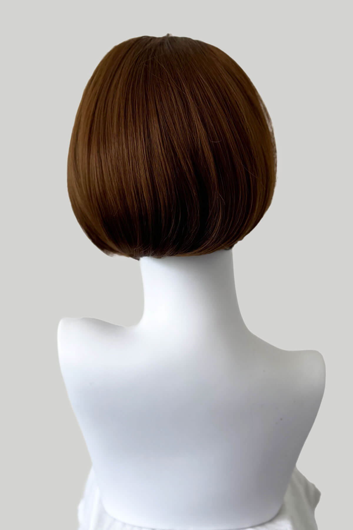 Brown wig on a white mannequin head against a plain background. Bob half wig hairpiece, heat styleable: Amelie light chocolate brown 12