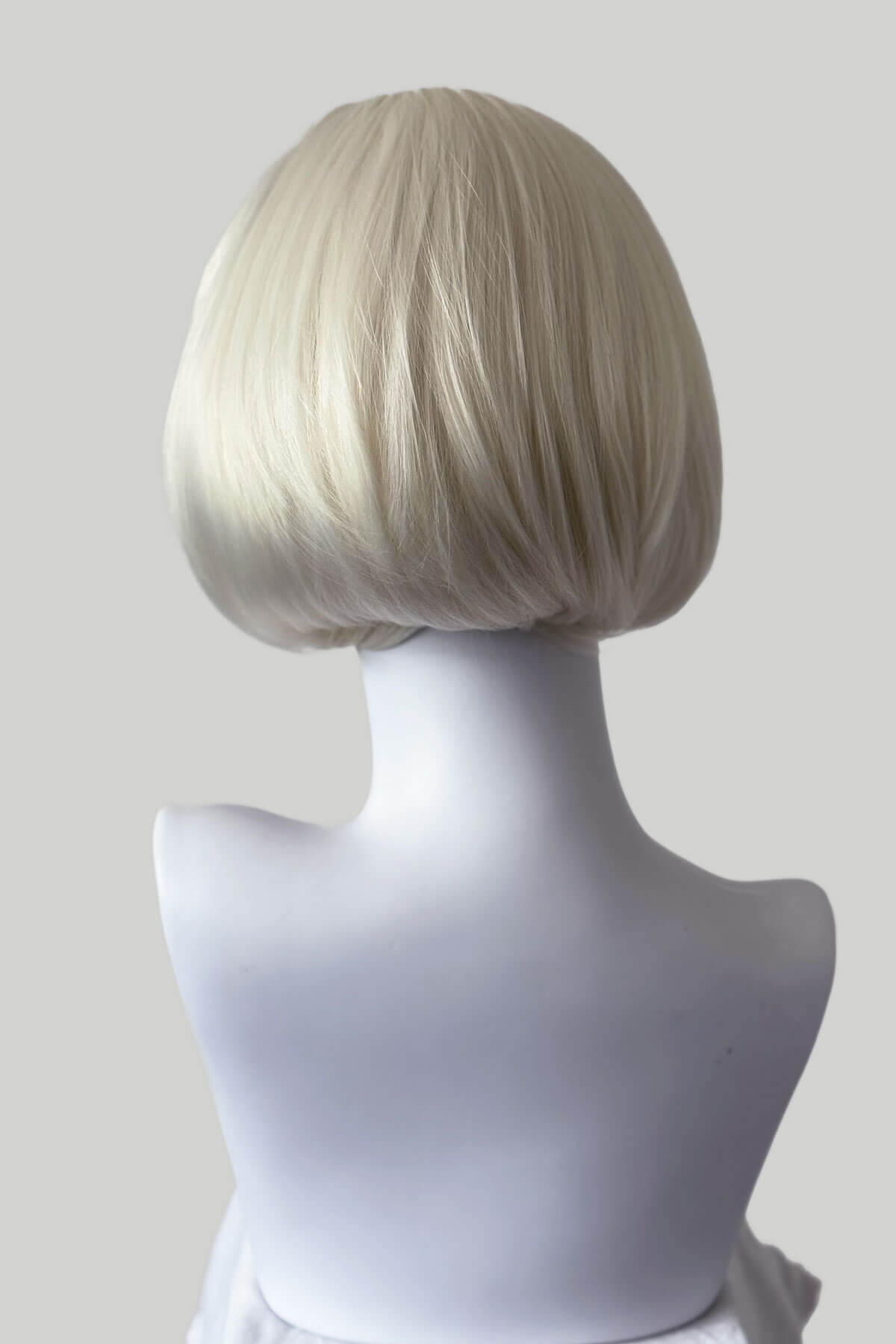 Blonde wig on a mannequin head against a plain background. Bob half wig hairpiece, heat styleable: Amelie platinum blonde 1001